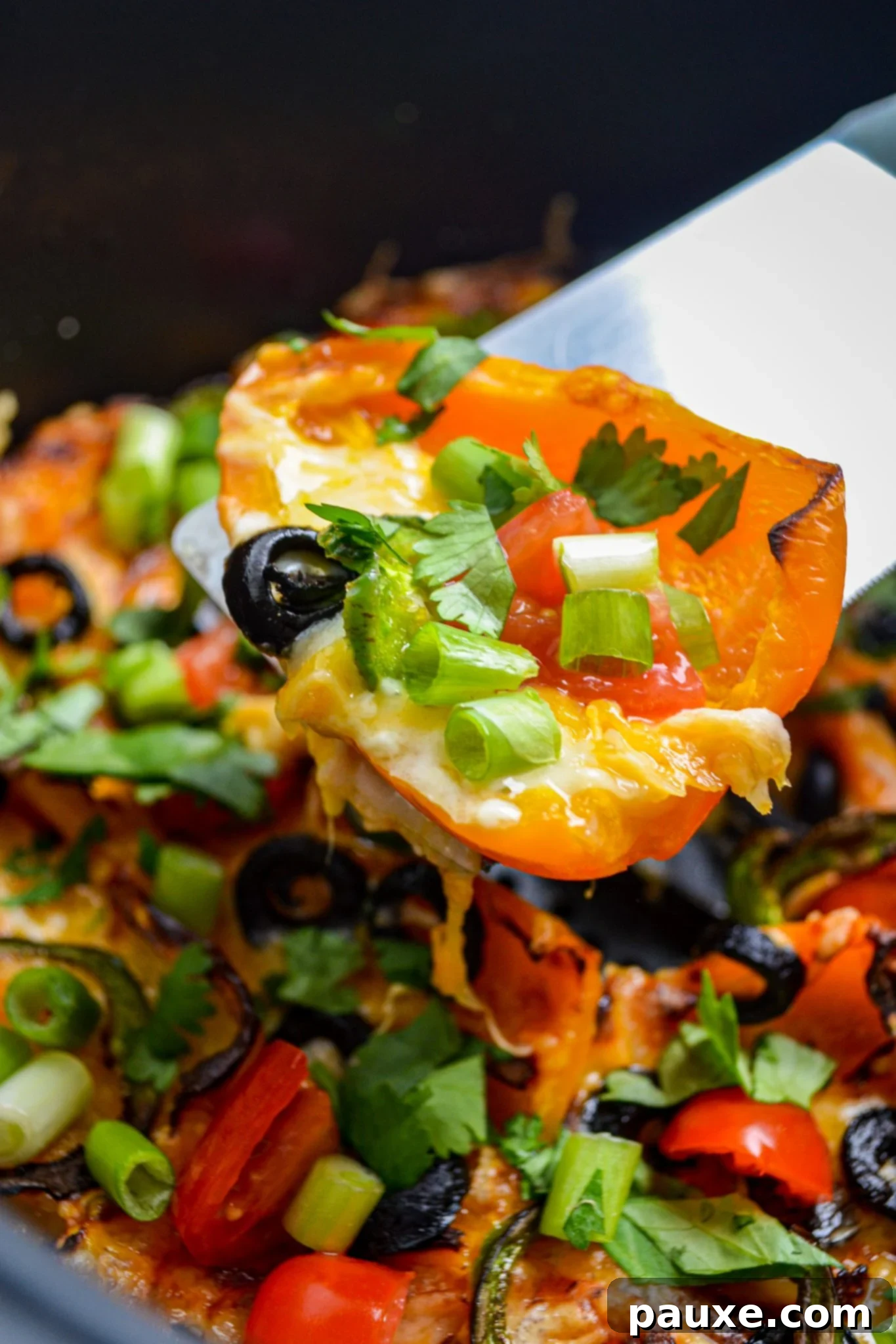Loaded Air Fryer Mini Bell Pepper Nachos 7 A spatula lifting a portion of cheesy mini pepper nachos from the air fryer.