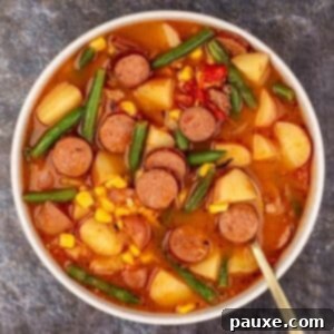 Mossy Potage 12 A bowl of hearty stew featuring sliced smoked sausage, potato, green bean, and corn, ready to be enjoyed.