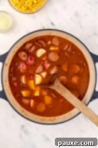 Mossy Potage 15 A dutch oven with soup inside, featuring chunks of potato and sliced smoked sausage.