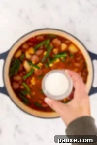 Mossy Potage 17 A small bowl of cornstarch hovering over a large Dutch oven full of soup.