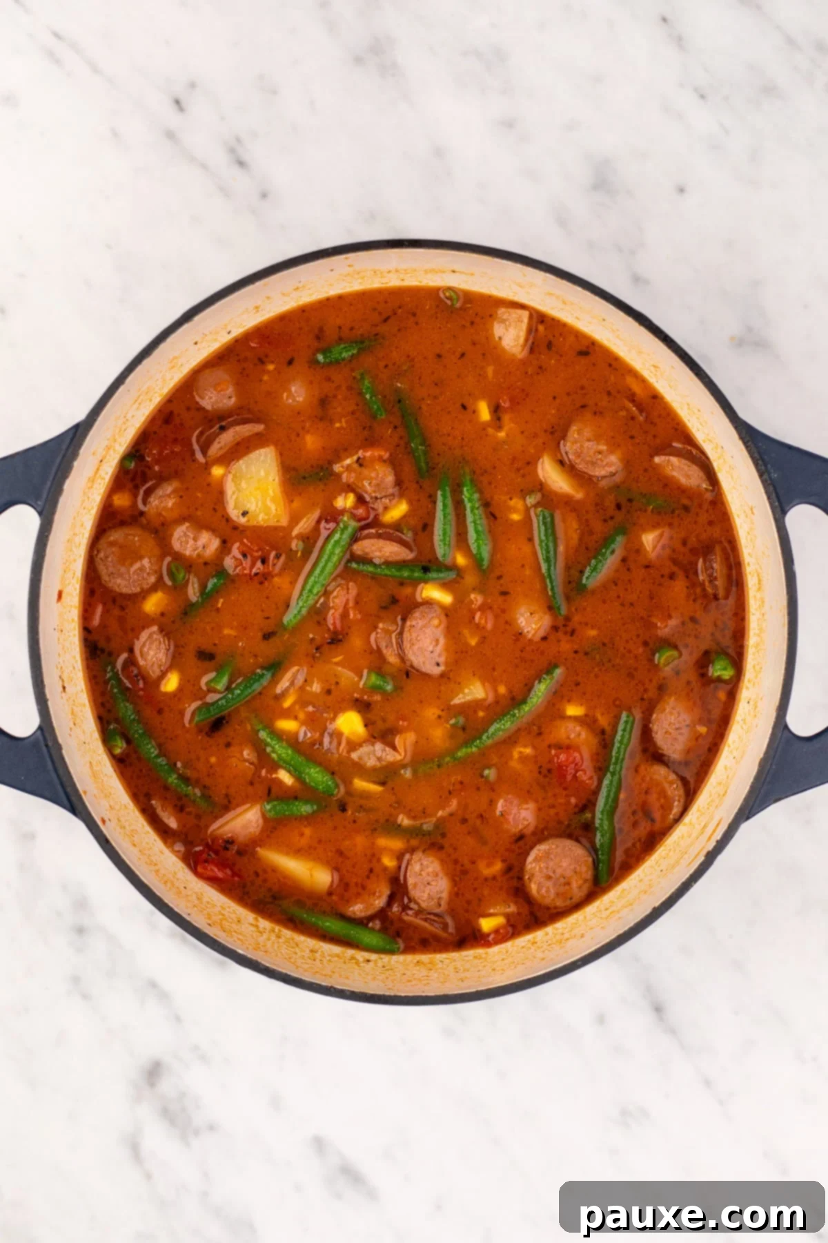Mossy Potage 9 A large, steaming Dutch oven filled with the completed hearty tomato and broth-based Swamp Soup, ready to be served.