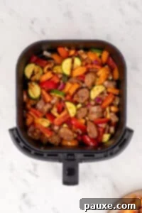 Air-Fried Chicken Sausage & Roasted Veggies 13 An air fryer basket filled with chicken sausage and vegetables, ready to cook.