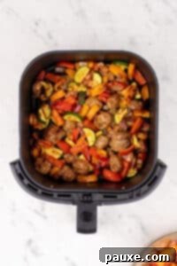 Air-Fried Chicken Sausage & Roasted Veggies 14 An air fryer basket filled with cooked chicken sausage and vegetables.