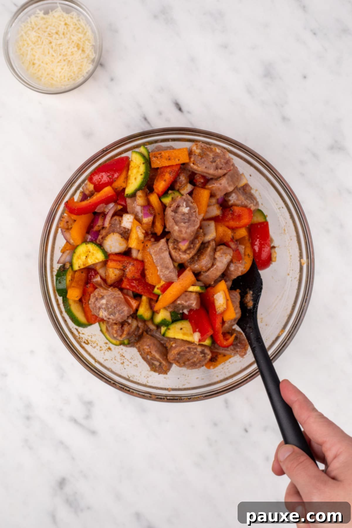 Air-Fried Chicken Sausage & Roasted Veggies 5 Chopped vegetables and sliced chicken sausage being gently tossed together in a bowl with seasoning.