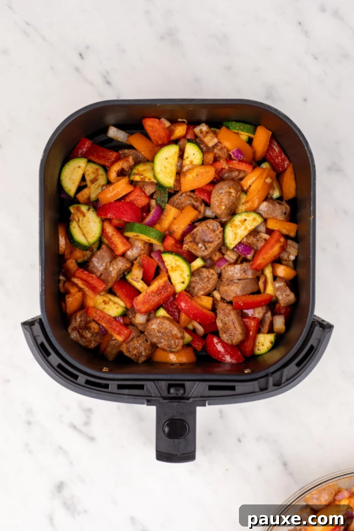Air-Fried Chicken Sausage & Roasted Veggies 6 An air fryer basket loaded with seasoned chicken sausage and vegetables, perfectly arranged for cooking.