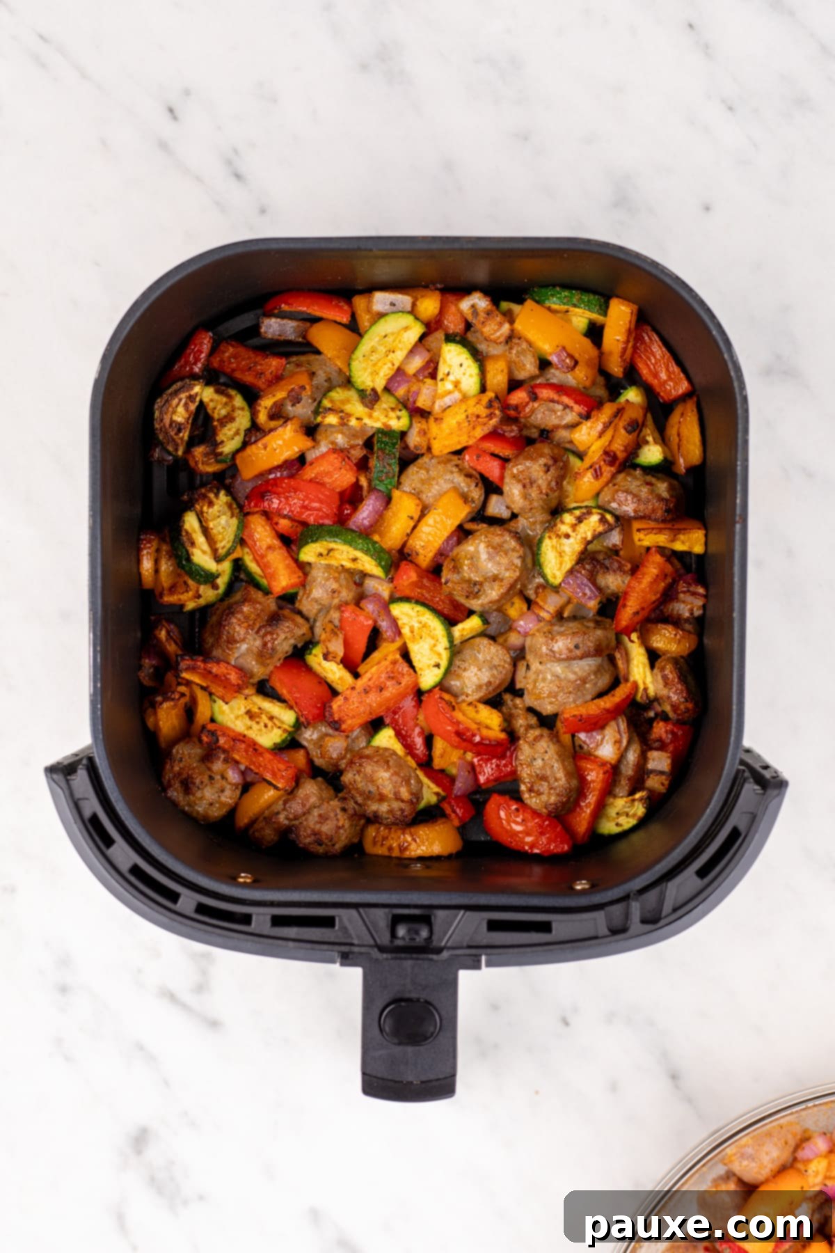 Air-Fried Chicken Sausage & Roasted Veggies 7 The golden-brown cooked chicken sausage and vegetables resting in the air fryer basket after cooking.