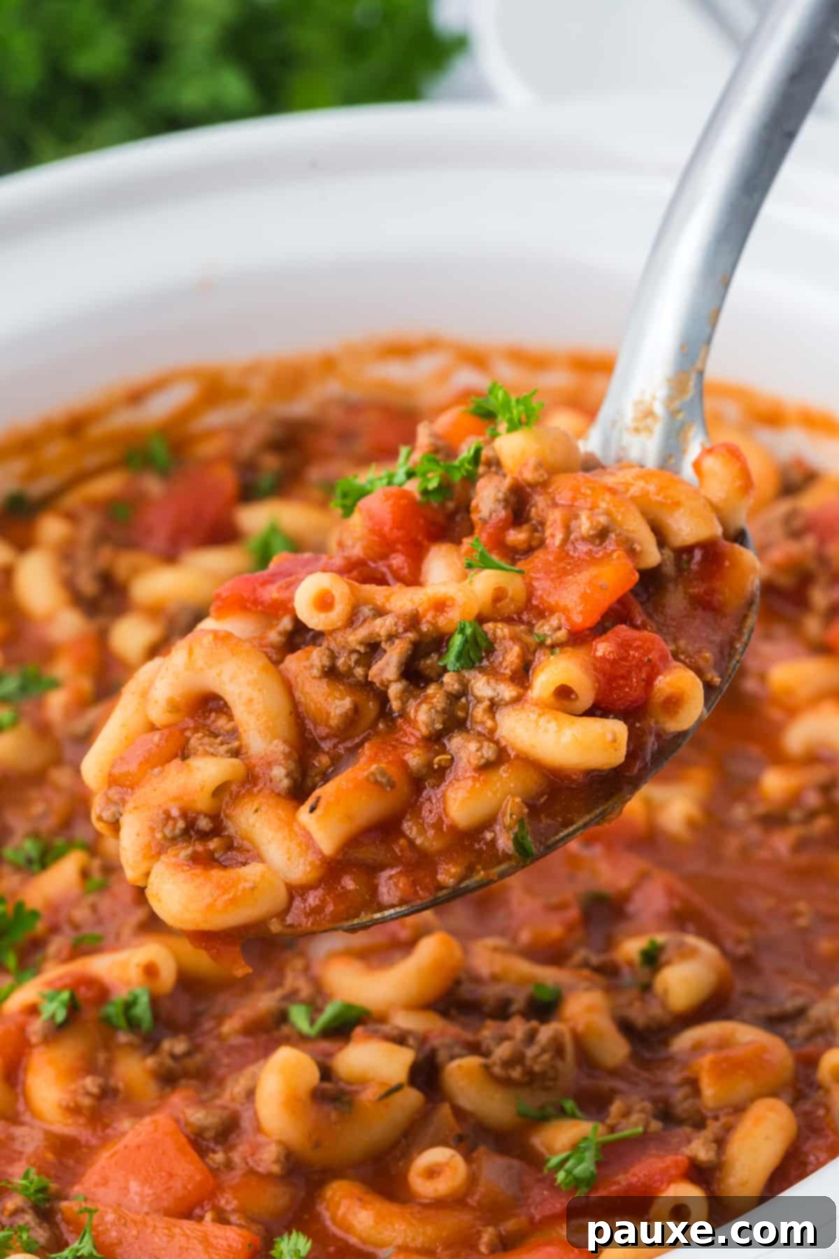 Homestyle Slow Cooker Goulash 7 A spoonful of American goulash being served from a slow cooker, showcasing its rich texture.