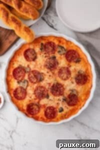 Baked Pepperoni Pizza Dip 16 Bubbly and hot pizza dip in a round white baking dish, with garlic breadsticks on the side.