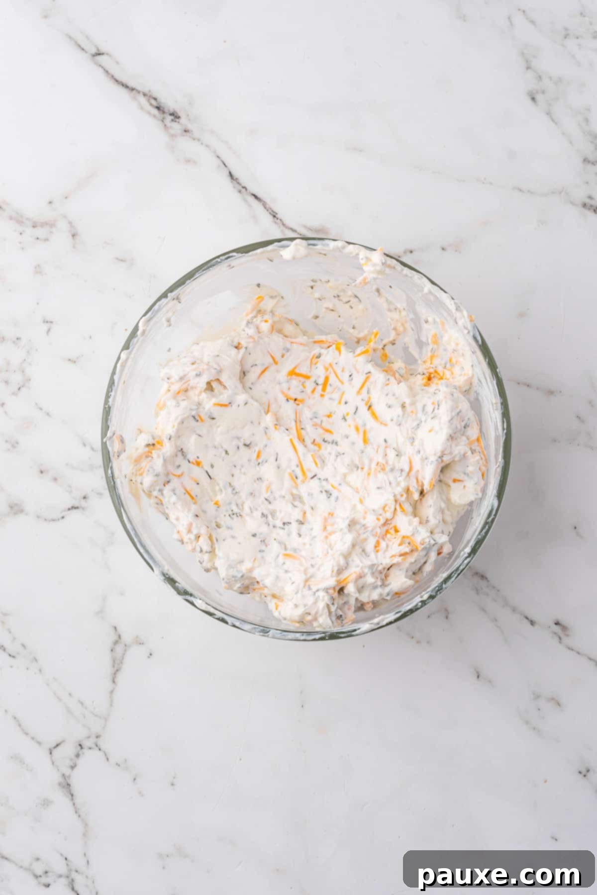 Baked Pepperoni Pizza Dip 4 A bowl of softened cream cheese mixed with sour cream, Italian seasoning, and garlic powder, ready to be spread.