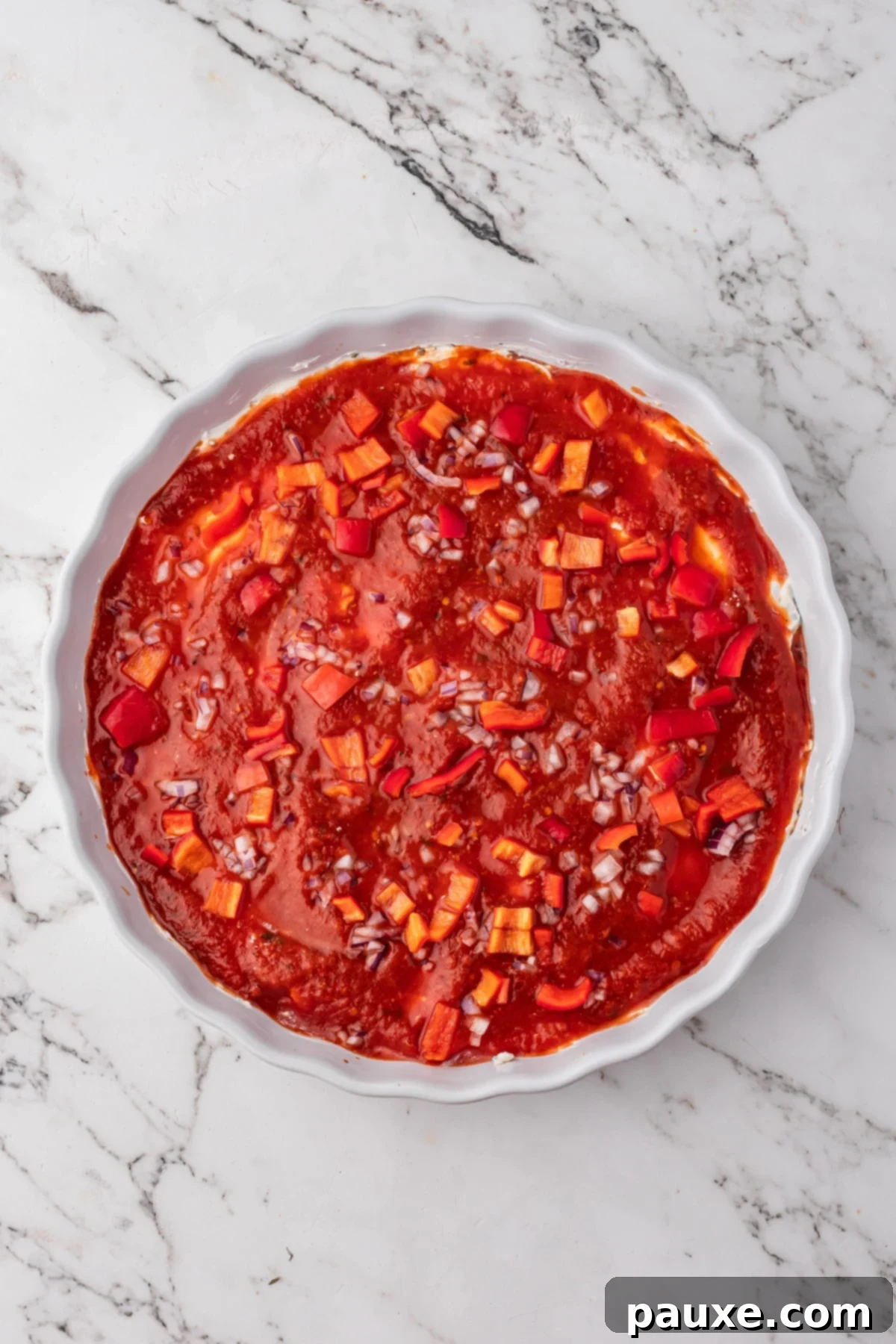 Baked Pepperoni Pizza Dip 6 A baking dish with the cream cheese base, topped with a layer of pizza sauce and various pizza toppings.