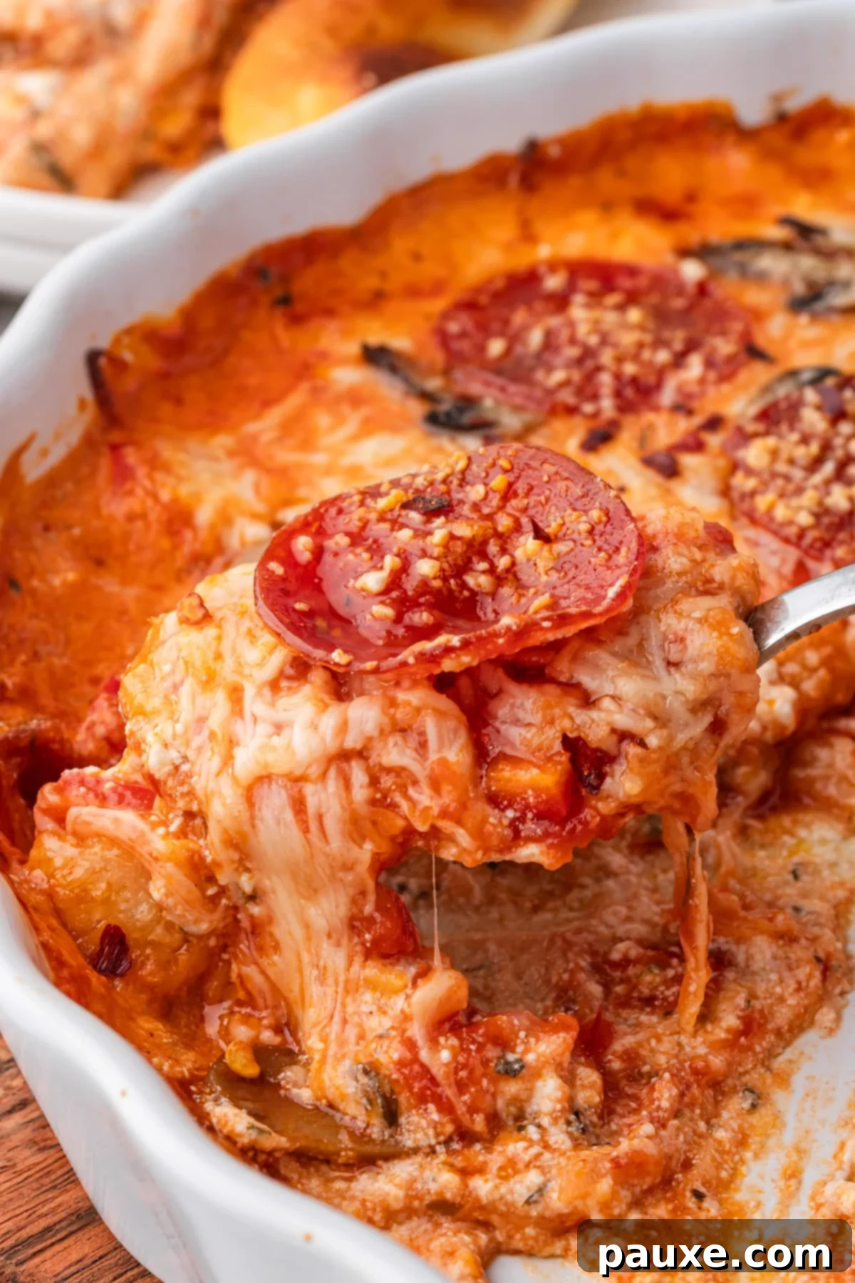 Baked Pepperoni Pizza Dip 9 A serving spoon lifting a generous scoop of gooey, melted cheese and pepperoni from the hot baked pizza dip, showcasing its irresistible texture.