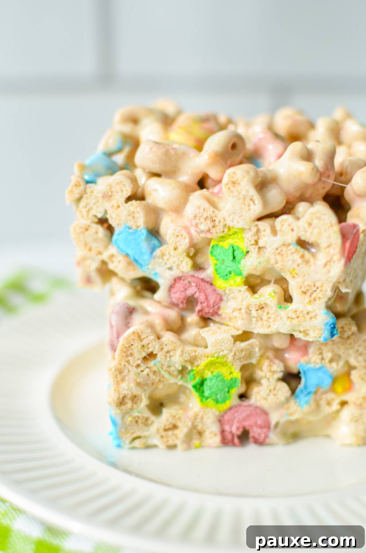 Magical Marshmallow Bites 8 Two Lucky Charms treats stacked on a white plate, ready to be eaten, with a tiled background.