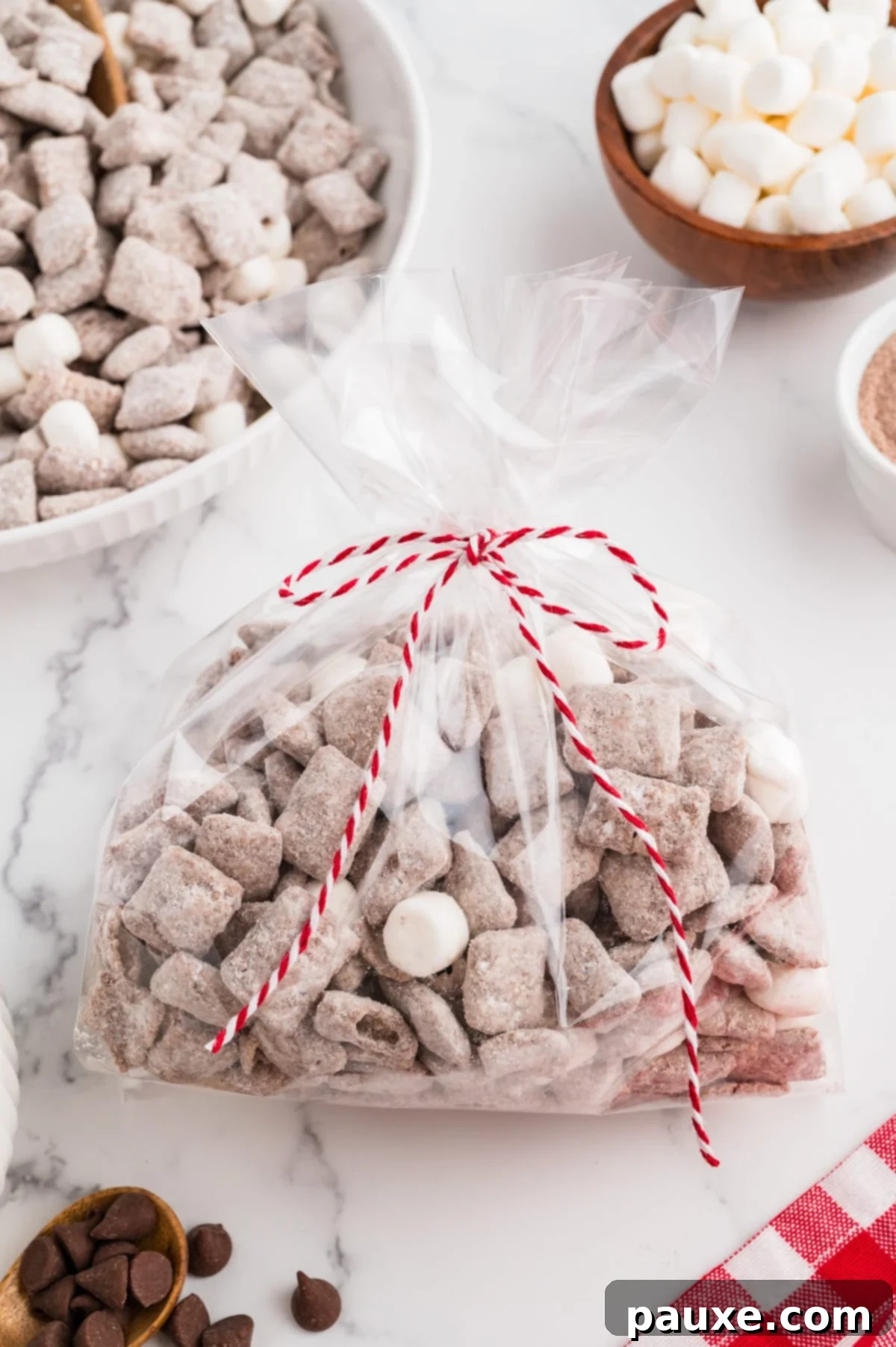 A cellophane gift bag filled with muddy buddies and tied with a decorative string.