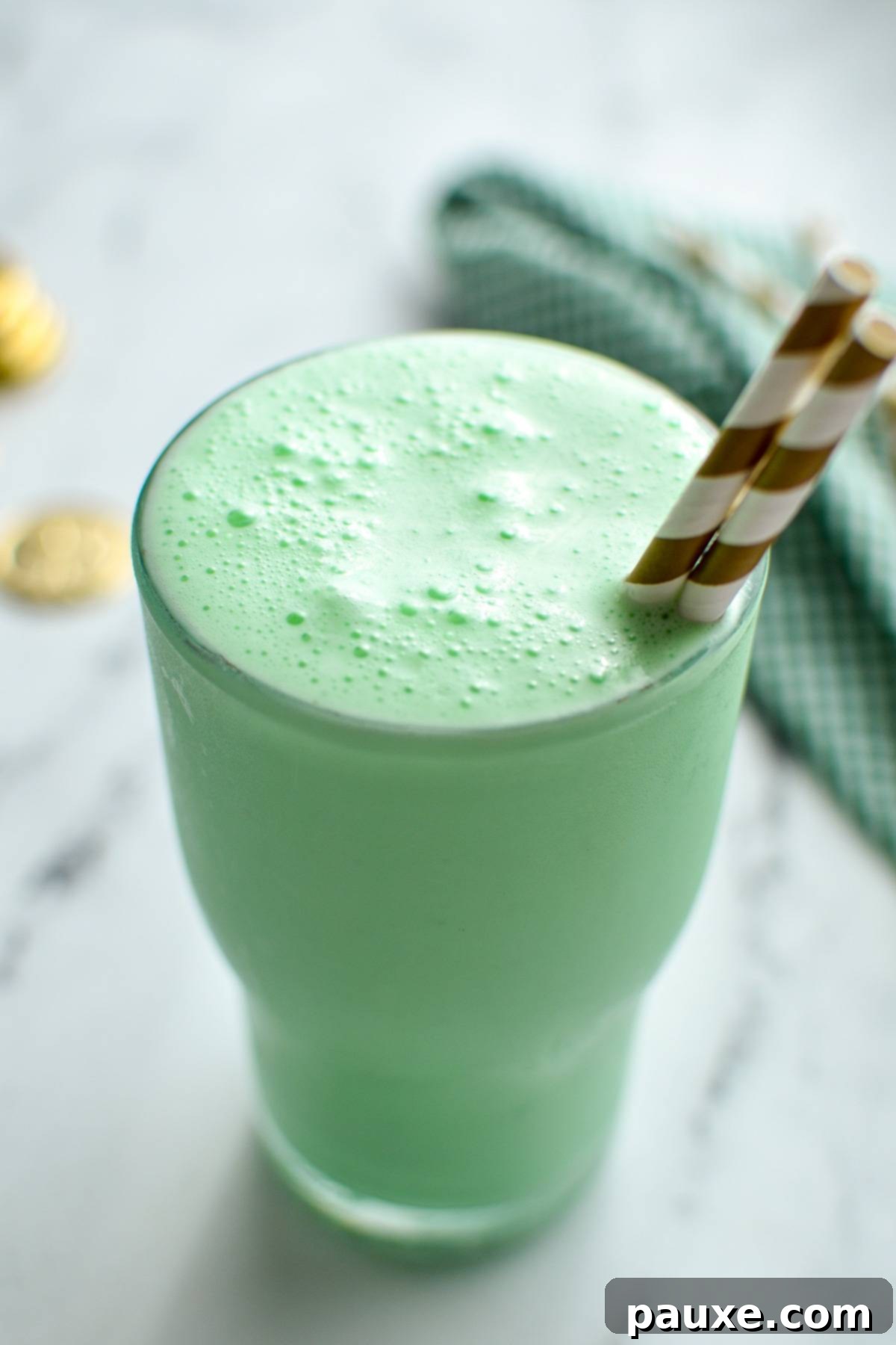 Whip Up Your Own McDonald's Shamrock Shake 6 A glass filled with a green milkshake, with a gold striped set of straws sticking out.