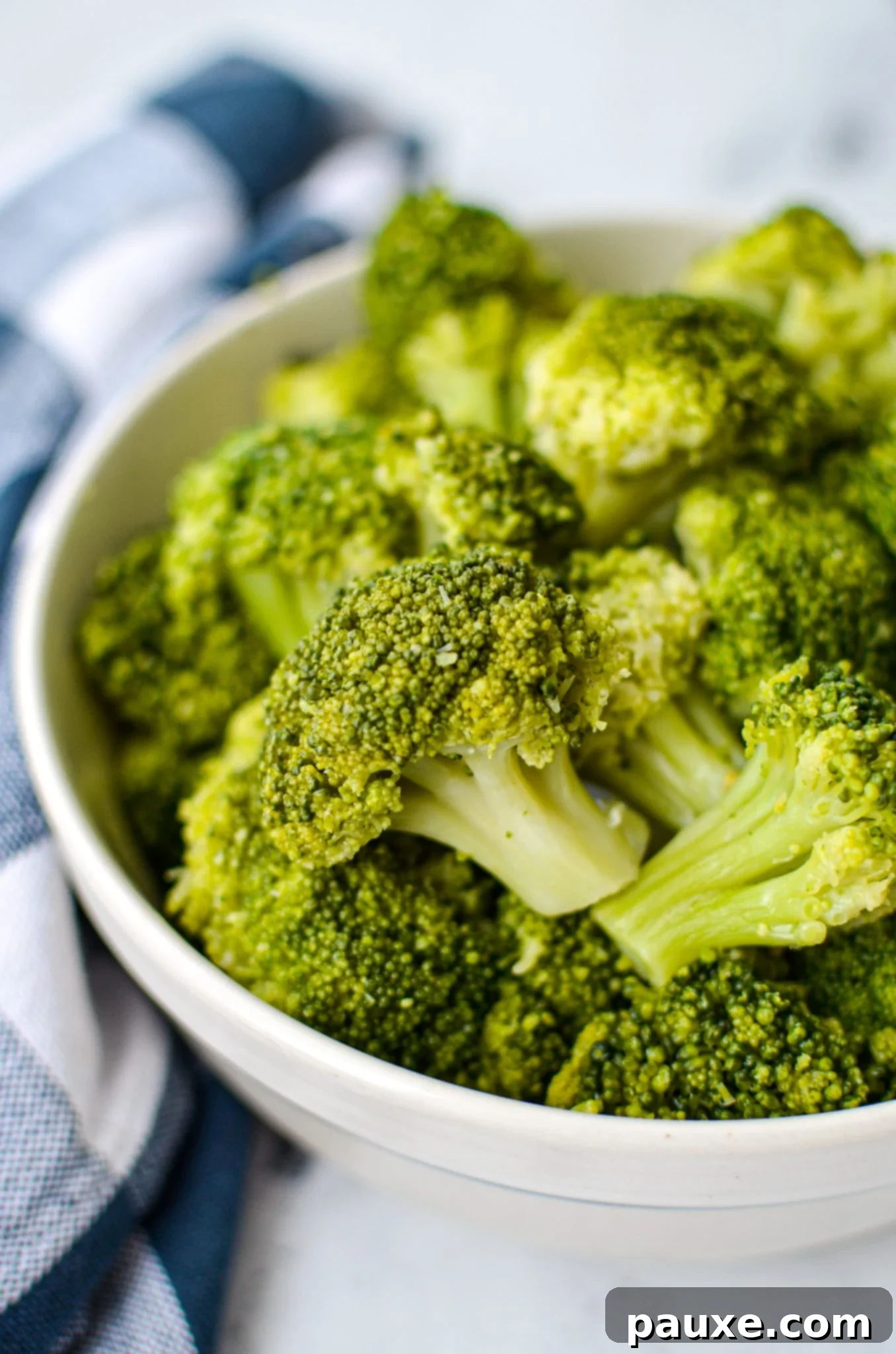 Perfect Instant Pot Frozen Broccoli 2 A bowl of cooked broccoli, resting on a blue check napkin, perfectly steamed and bright green.