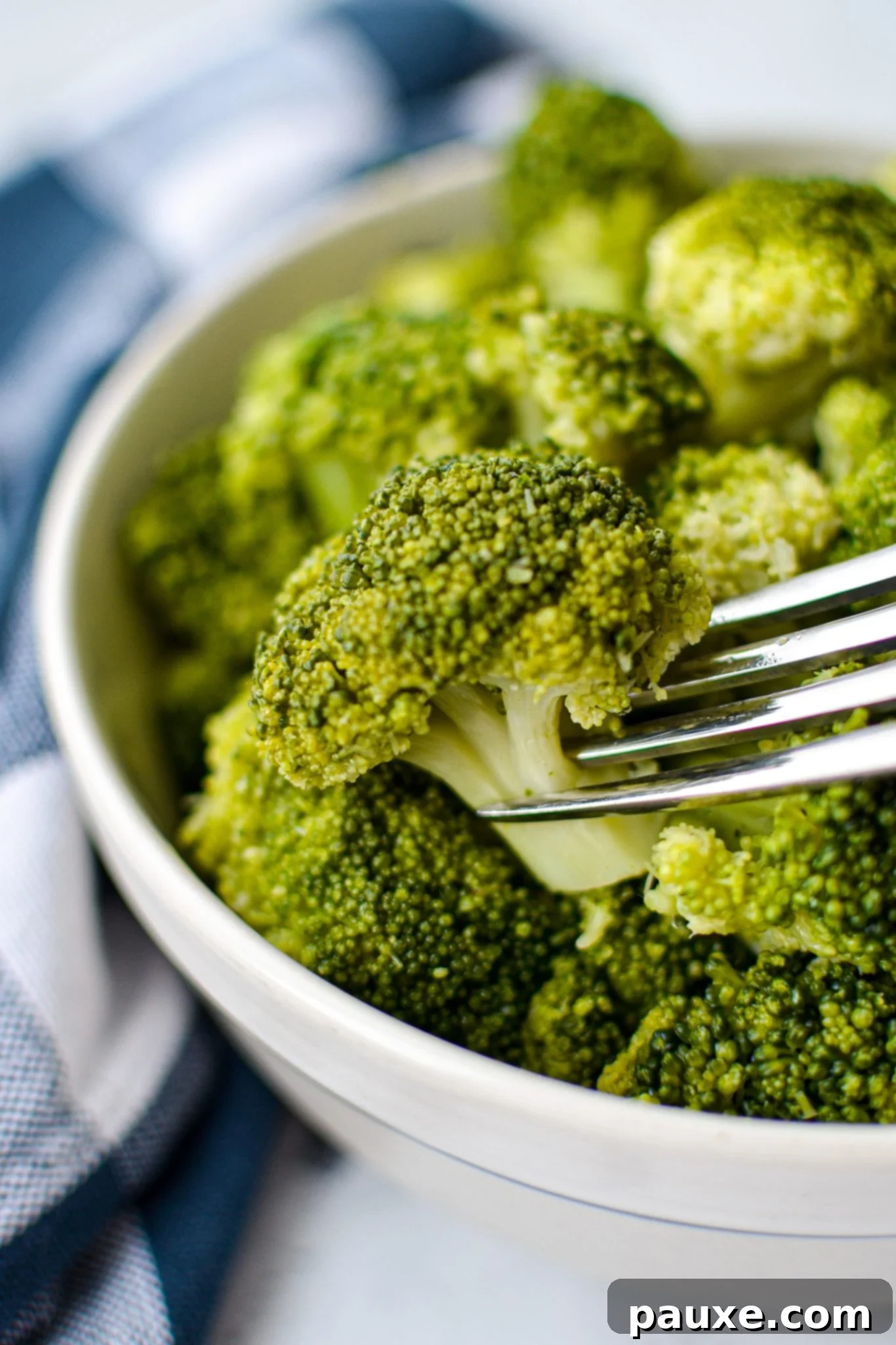 Perfect Instant Pot Frozen Broccoli 11 A bowl of cooked broccoli, with a fork taking a piece, showing its tender texture.