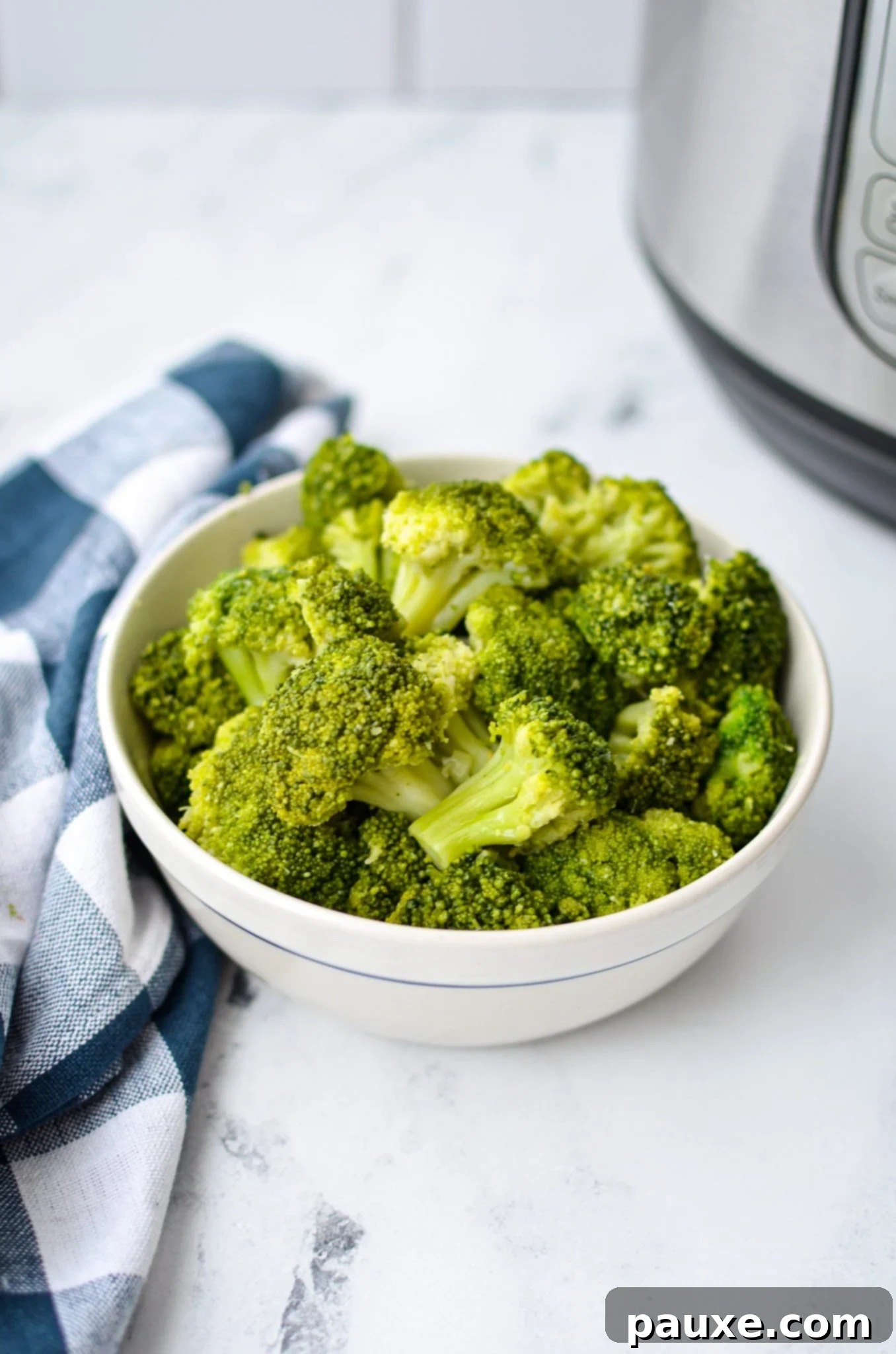 Perfect Instant Pot Frozen Broccoli 12 A bowl of cooked broccoli resting on a counter with an Instant Pot in the background, ready to be served or incorporated into a meal.