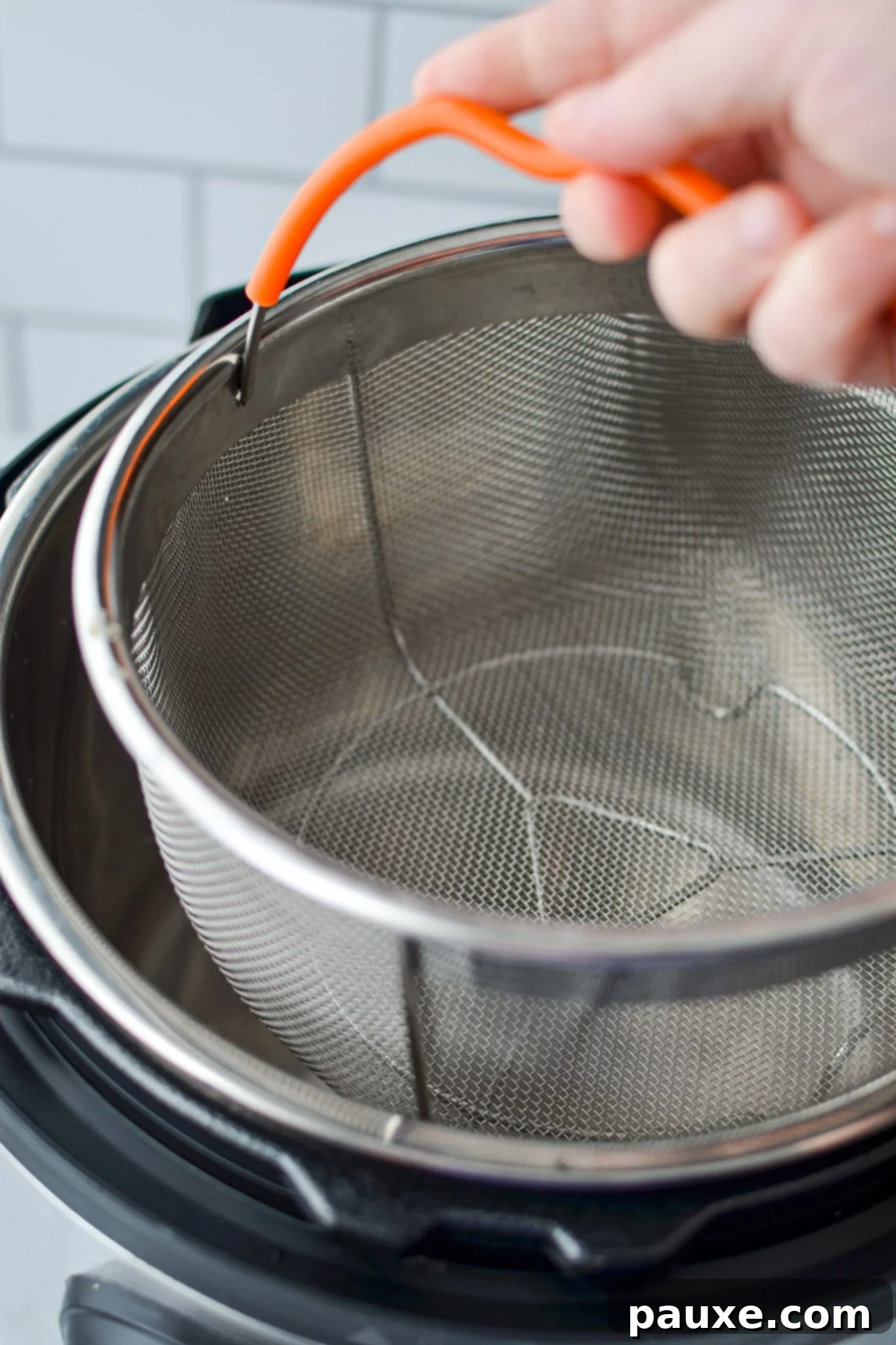 Perfect Instant Pot Frozen Broccoli 7 Lowering a steamer basket into the insert of an Instant Pot, resting on the trivet.
