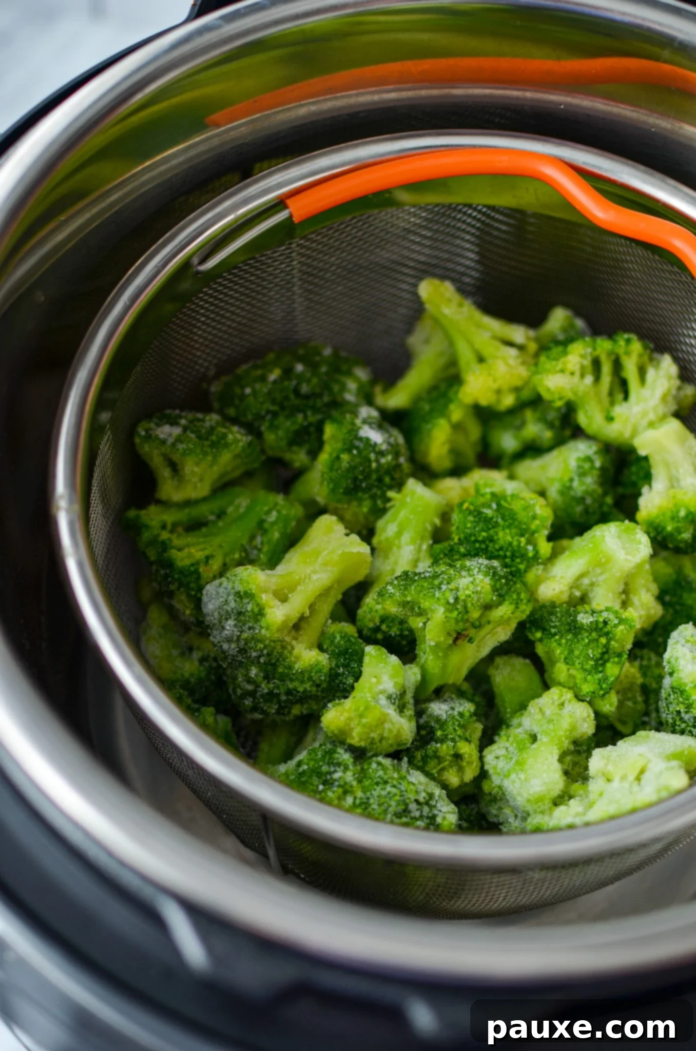 Perfect Instant Pot Frozen Broccoli 8 Frozen broccoli resting inside the insert of a steamer basket within an Instant Pot, ready for cooking.