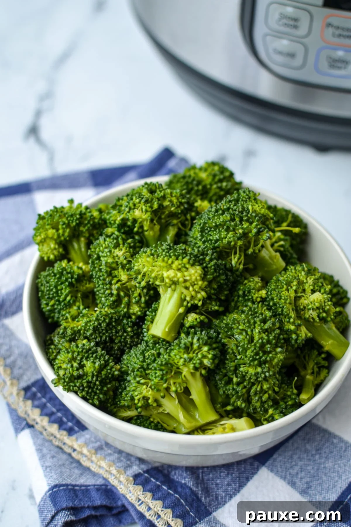 Effortless Instant Pot Broccoli 2 A bowl of freshly steamed broccoli with an Instant Pot visible in the soft background.