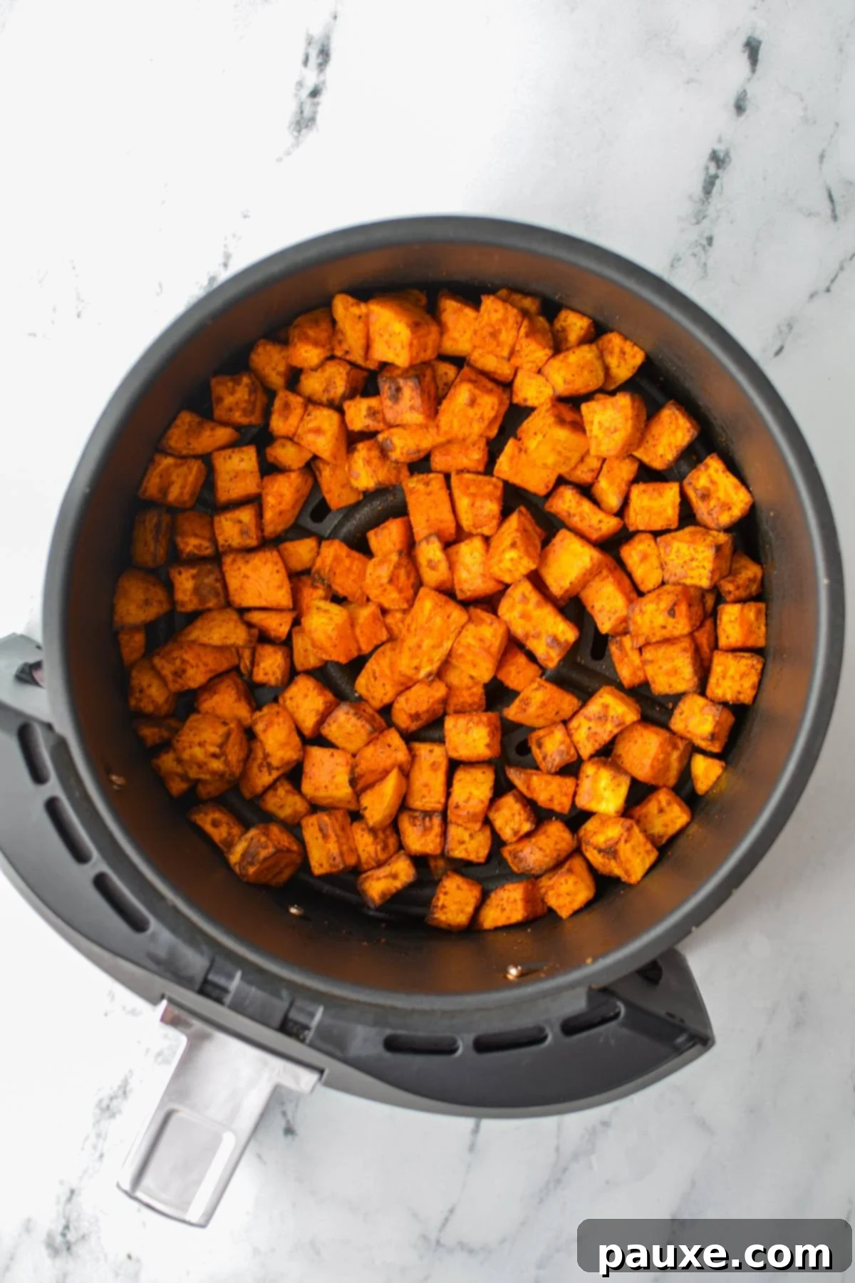 Crispy Air Fryer Sweet Potato Cubes 9 A close-up view of perfectly roasted, golden sweet potato chunks nestled in an air fryer basket.