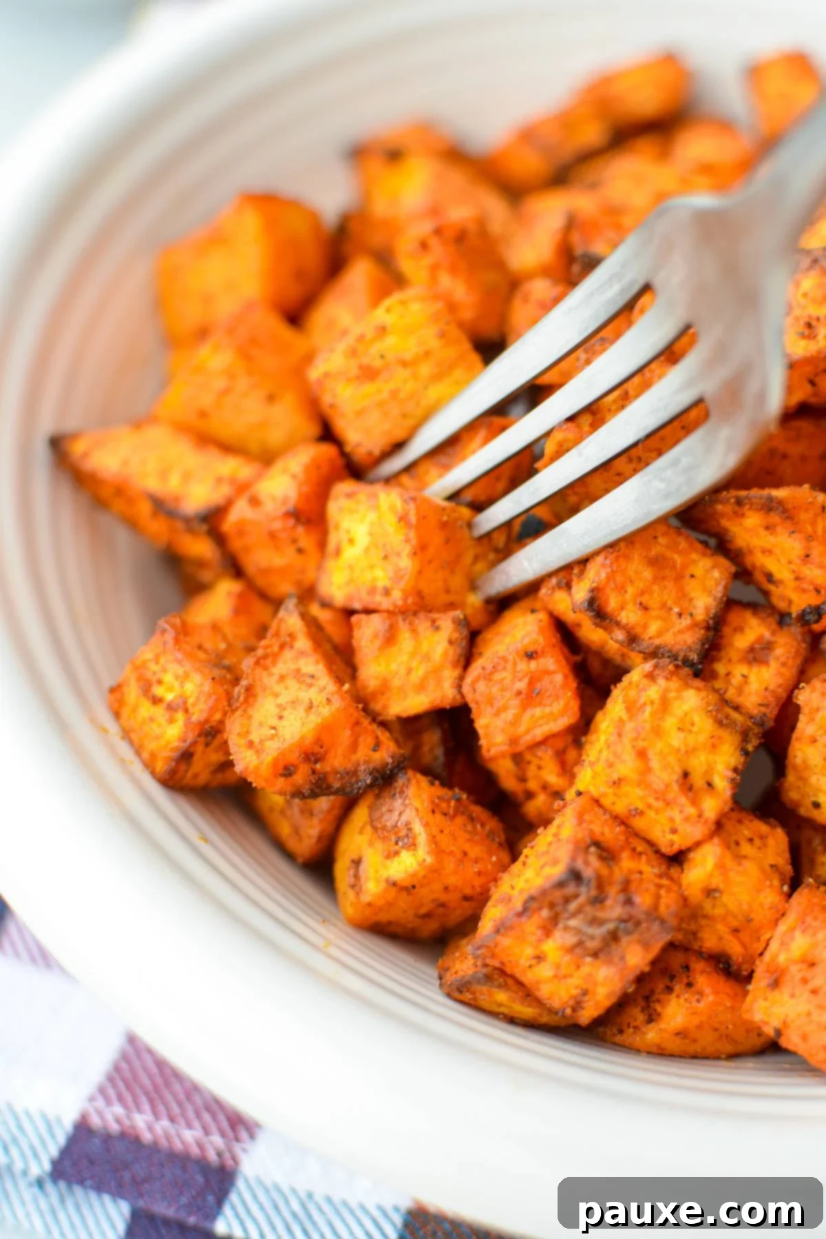 Crispy Air Fryer Sweet Potato Cubes 10 A fork gently piercing into a perfectly roasted sweet potato cube, highlighting its tender interior.