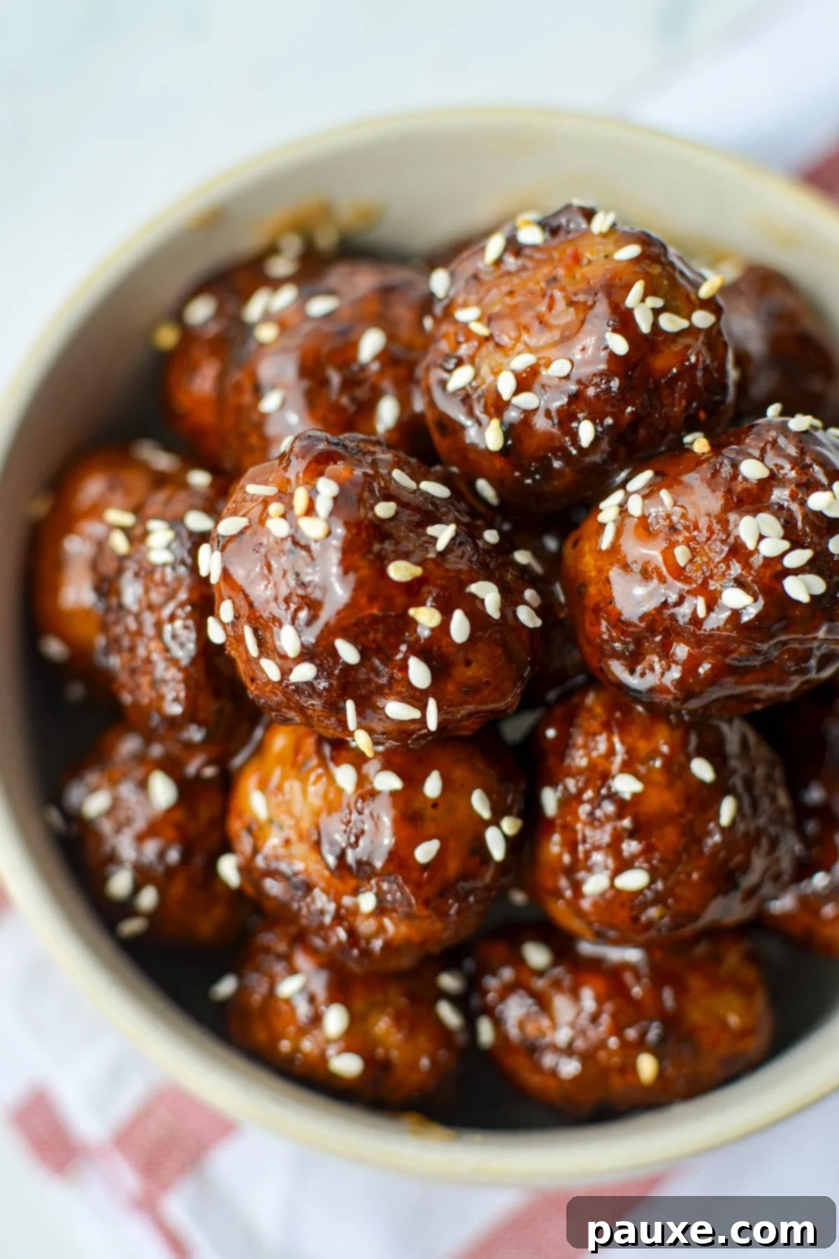 Perfect Air Fryer Frozen Meatballs 2 A bowl of glazed meatballs, garnished with sesame seeds and fresh herbs, ready to be served.
