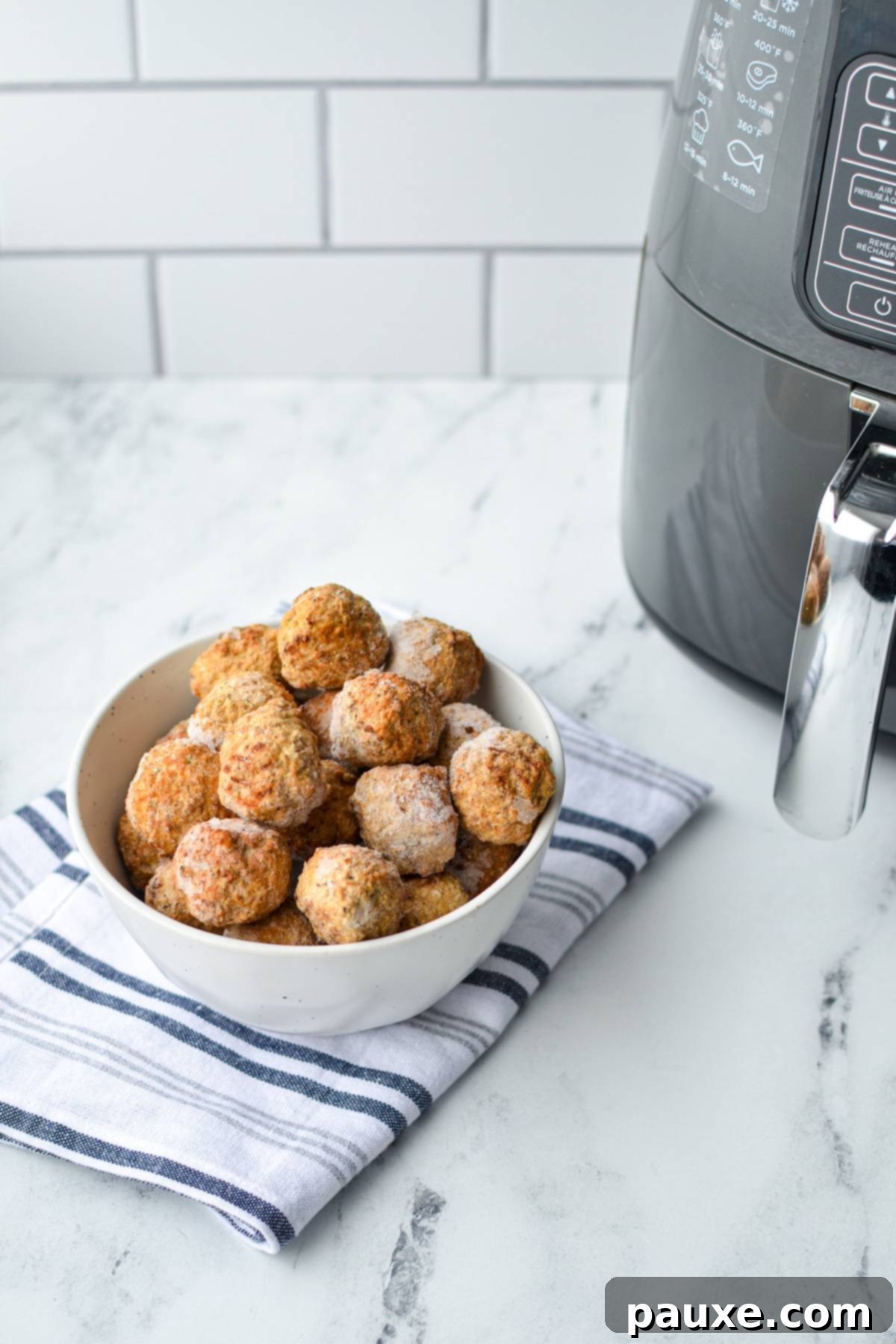 Perfect Air Fryer Frozen Meatballs 3 A bowl of frozen meatballs on a white and blue checkered napkin, with an air fryer subtly visible in the background.