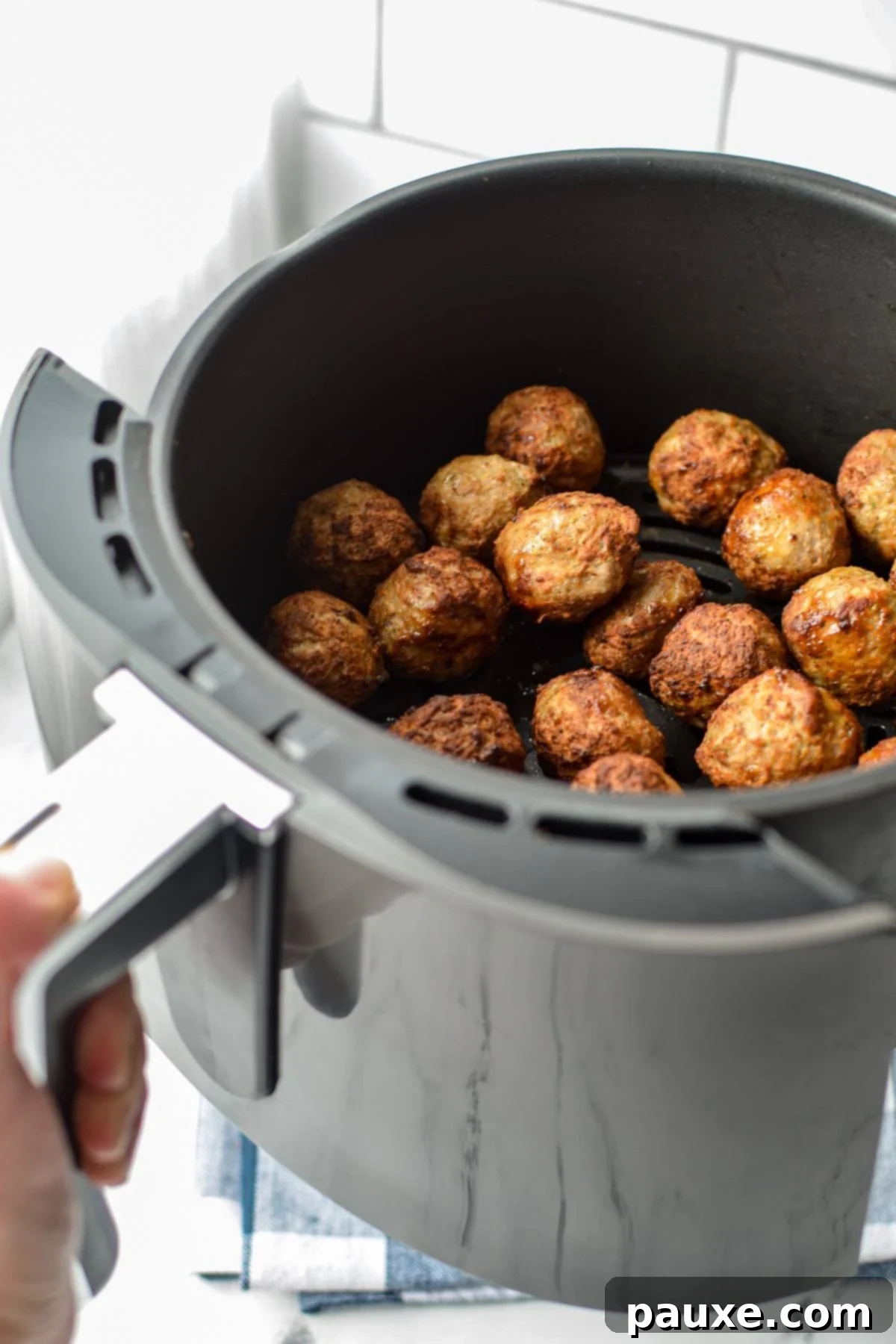 Perfect Air Fryer Frozen Meatballs 4 Shaking an air fryer basket full of frozen meatballs to ensure even cooking and browning.
