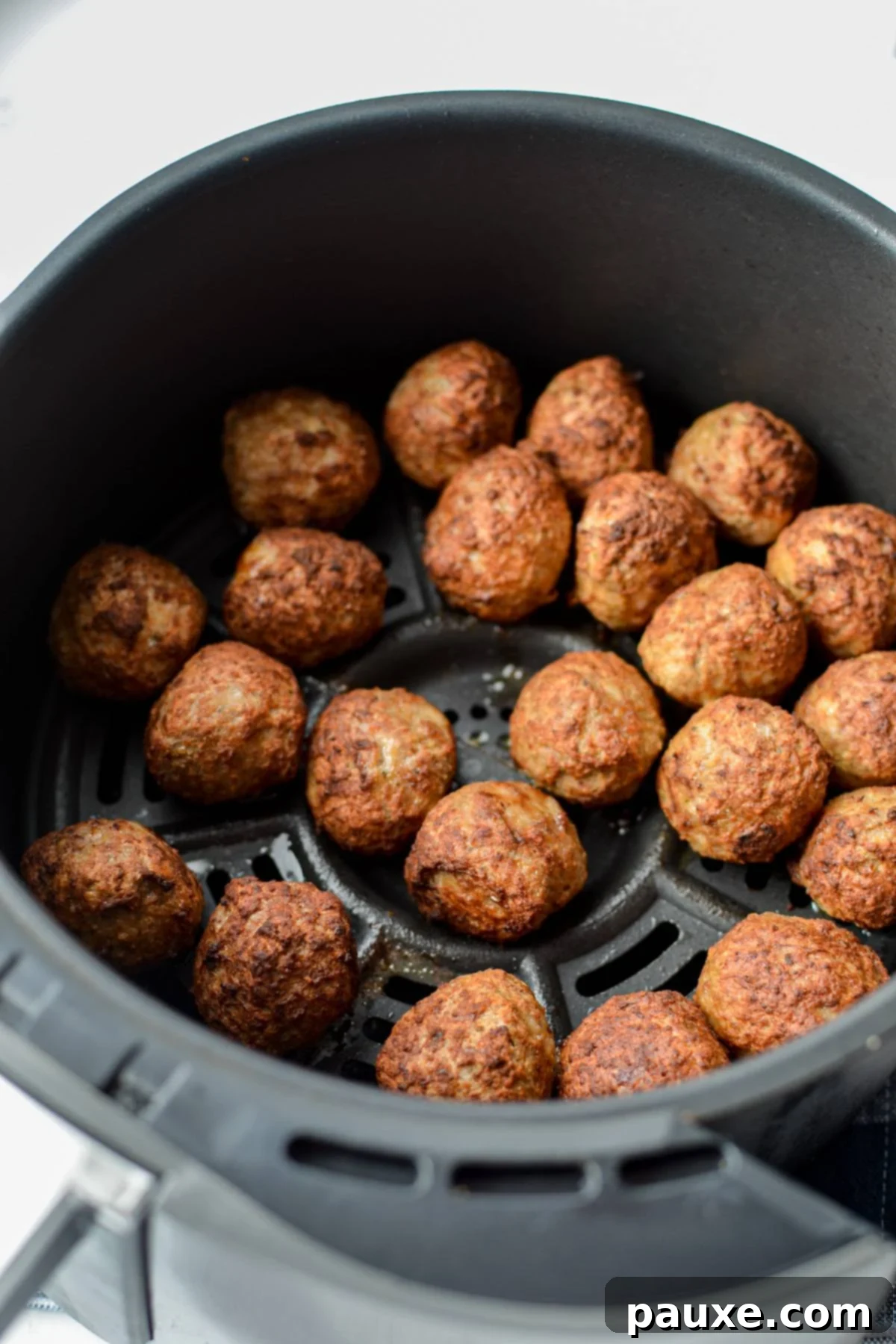 Perfect Air Fryer Frozen Meatballs 5 An air fryer basket filled with perfectly cooked and browned frozen meatballs, ready for serving.