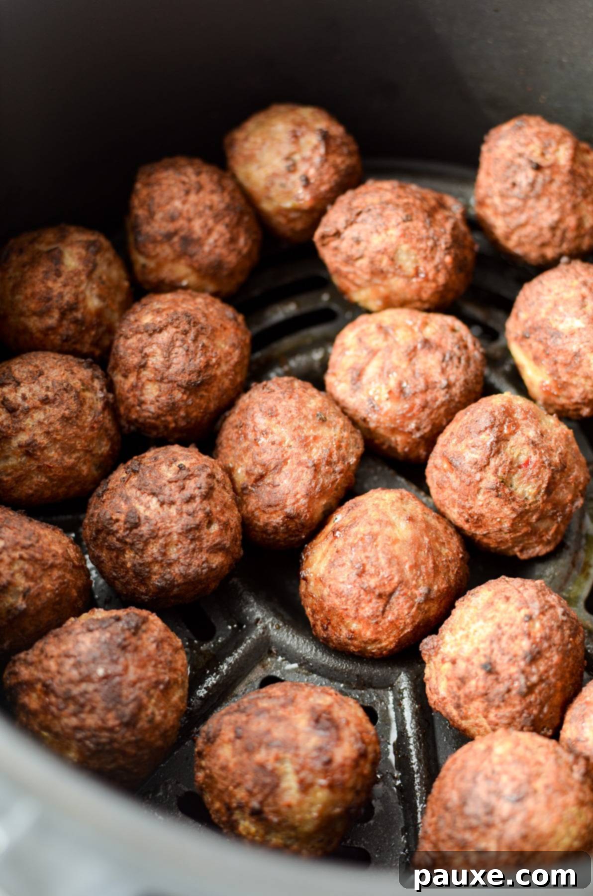 Perfect Air Fryer Frozen Meatballs 7 A close-up view of perfectly cooked and browned meatballs resting in an air fryer basket.