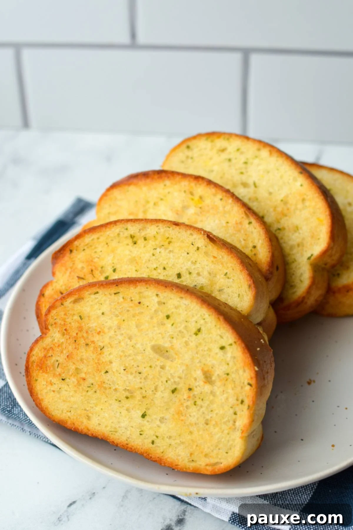 Crispy Air Fryer Texas Garlic Toast 2 A plate of perfectly toasted garlic toast, resting on a blue check napkin, ready to be enjoyed.