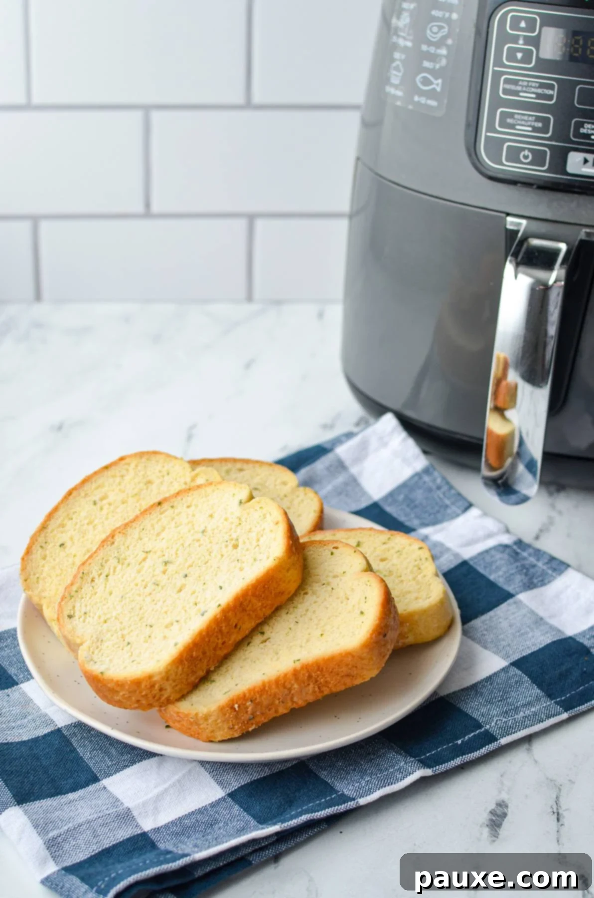 Crispy Air Fryer Texas Garlic Toast 3 A plate of frozen garlic toast on a plate, next to a basket style air fryer, showcasing the few items needed.
