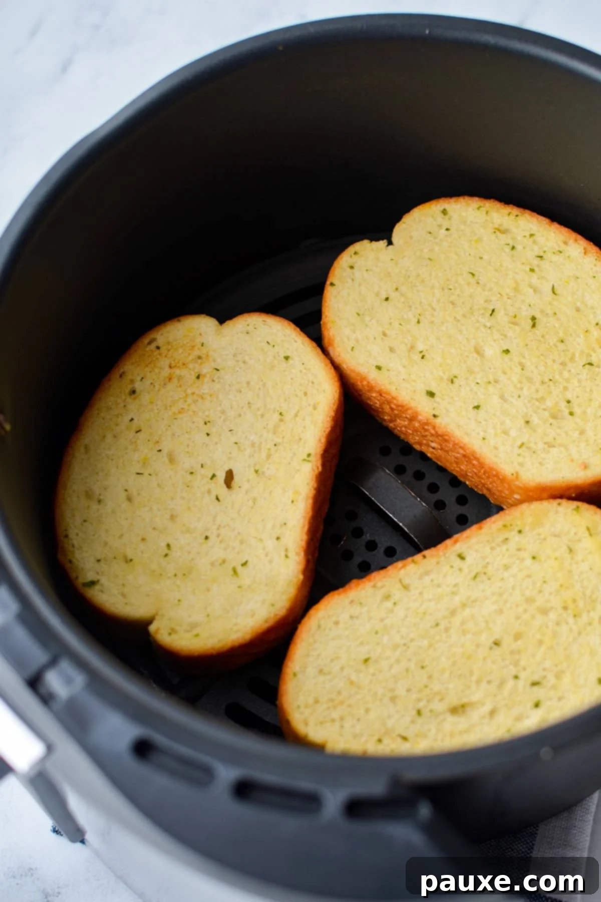 Crispy Air Fryer Texas Garlic Toast 5 3 slices of lightly toasted garlic bread in the basket of an air fryer, midway through the cooking process.