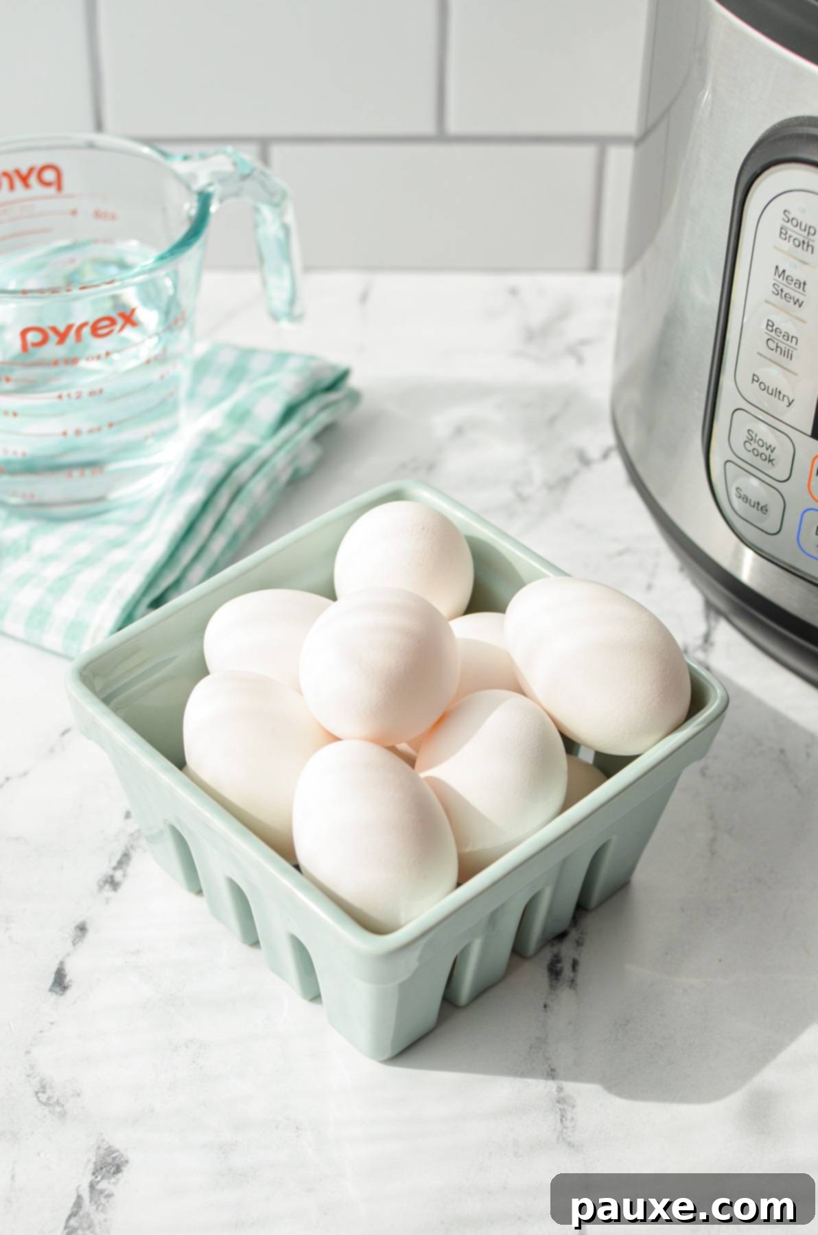 Effortless Instant Pot Deviled Eggs 4 Eggs in a carton with an Instant Pot and measuring cup of water in the background.