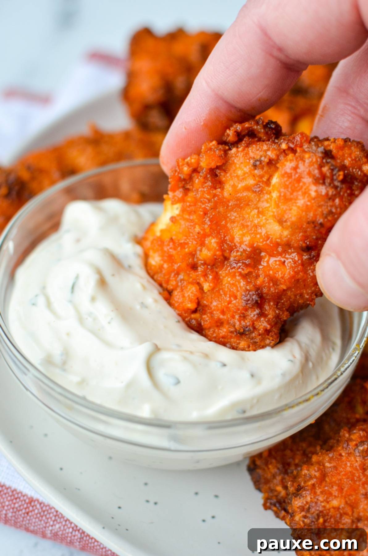 Dipping a buffalo chicken tender into a creamy ranch dip.