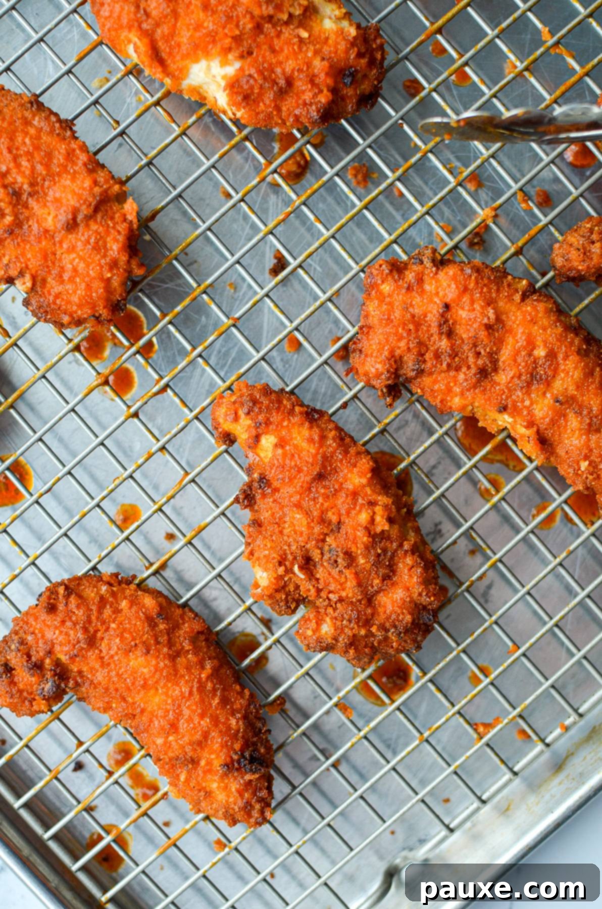 A wire rack filled with freshly coated air fryer buffalo chicken tenders.