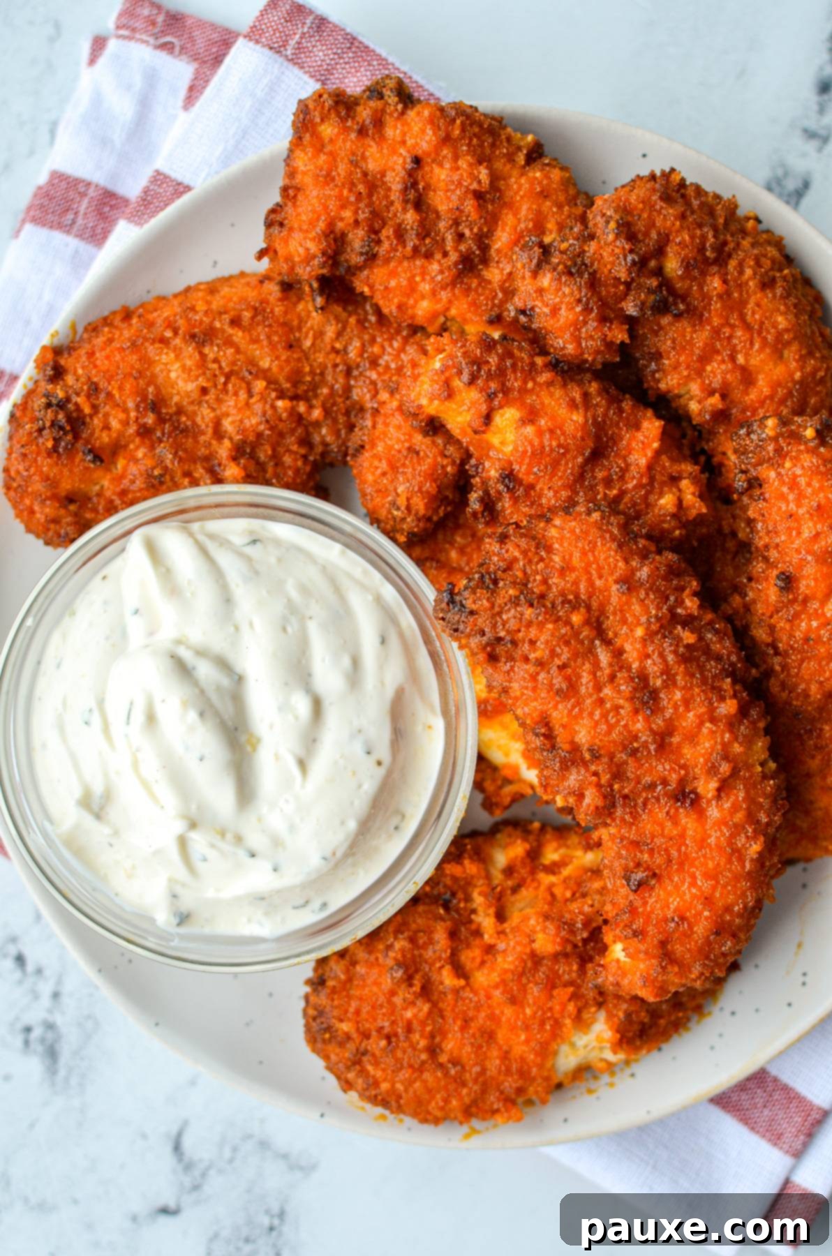 A plate of buffalo chicken tenders with a small bowl of ranch dip, garnished with parsley.