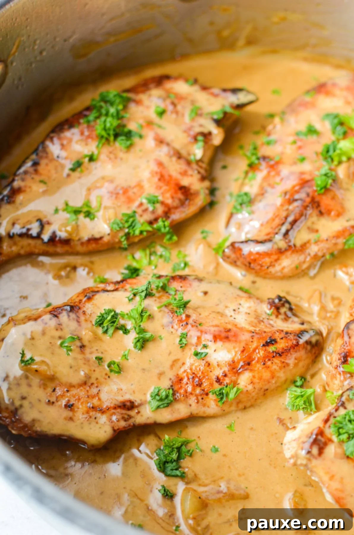 Simple Keto Low Carb Creamy Garlic Chicken Skillet 2 A close up of chicken in a skillet, coated in a light brown creamy garlic sauce.