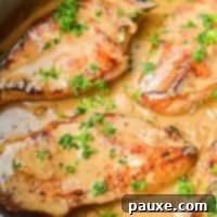 Simple Keto Low Carb Creamy Garlic Chicken Skillet 11 A close up of a skillet of chicken breasts in a creamy sauce, garnished with parsley.