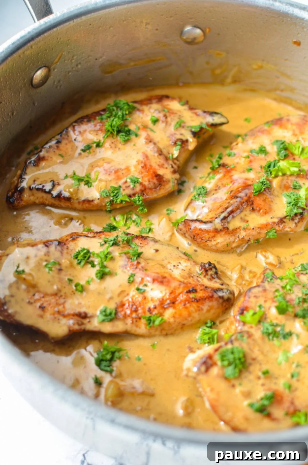 Simple Keto Low Carb Creamy Garlic Chicken Skillet 9 A skillet with chicken breasts and garlic sauce, sprinkled with parsley.