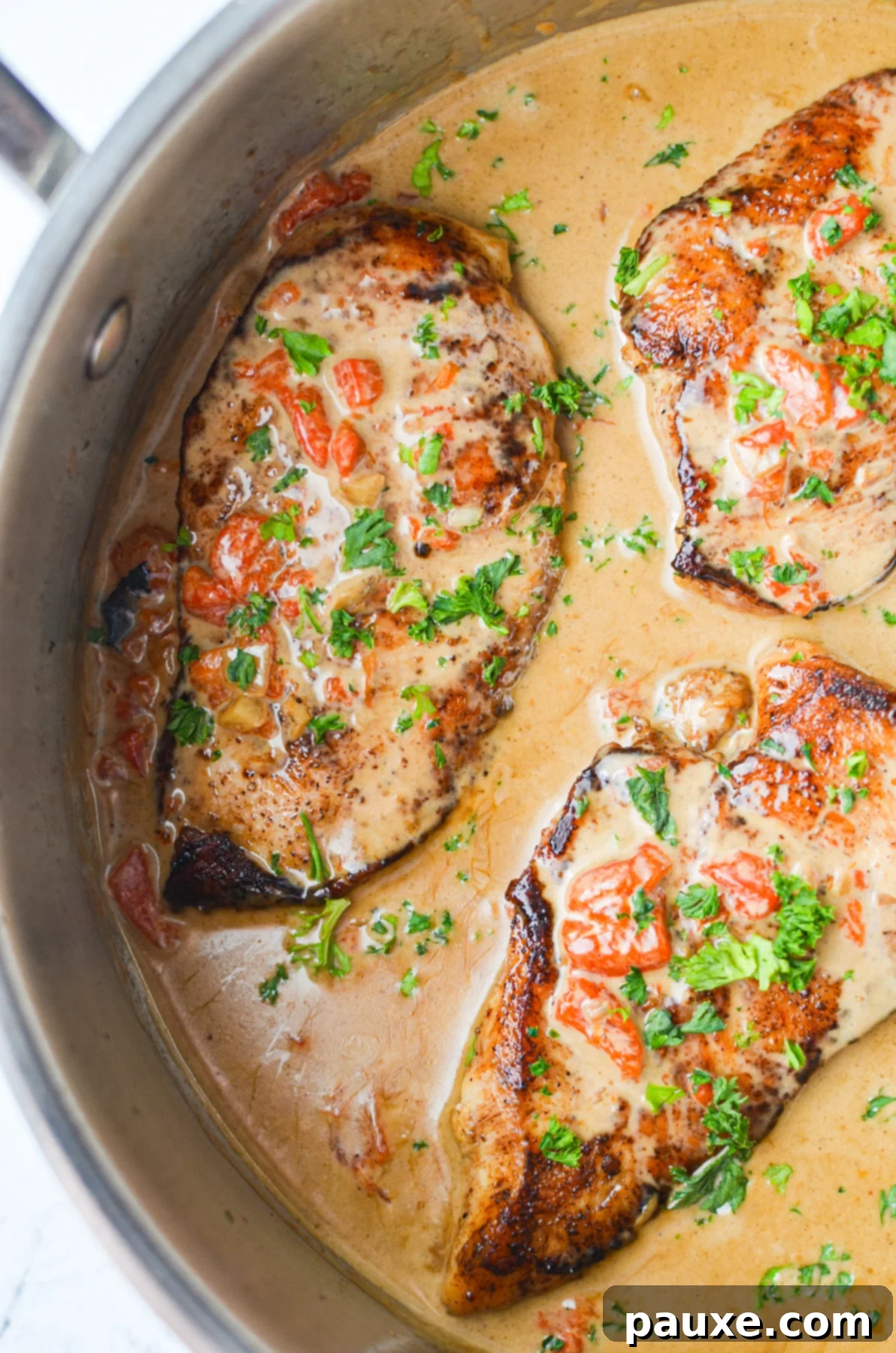 Velvety Roasted Red Pepper Chicken 2 A perfectly cooked chicken breast covered in a vibrant, creamy roasted red pepper sauce, garnished with fresh herbs, ready to be served in a skillet.