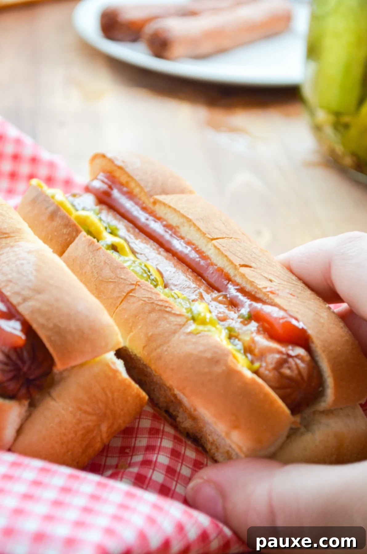 Crispy Air Fryer Hot Dogs and Toasted Buns 3 A hand reaching in for a fully dressed Air Fryer Hot Dog