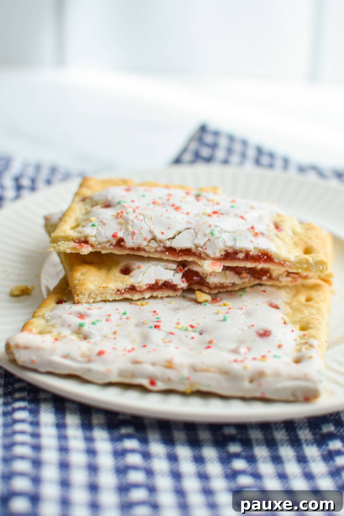 Air Fryer Toaster Pastries 2 A pop tart, broken in two, resting on top of another pop tart on a plate.