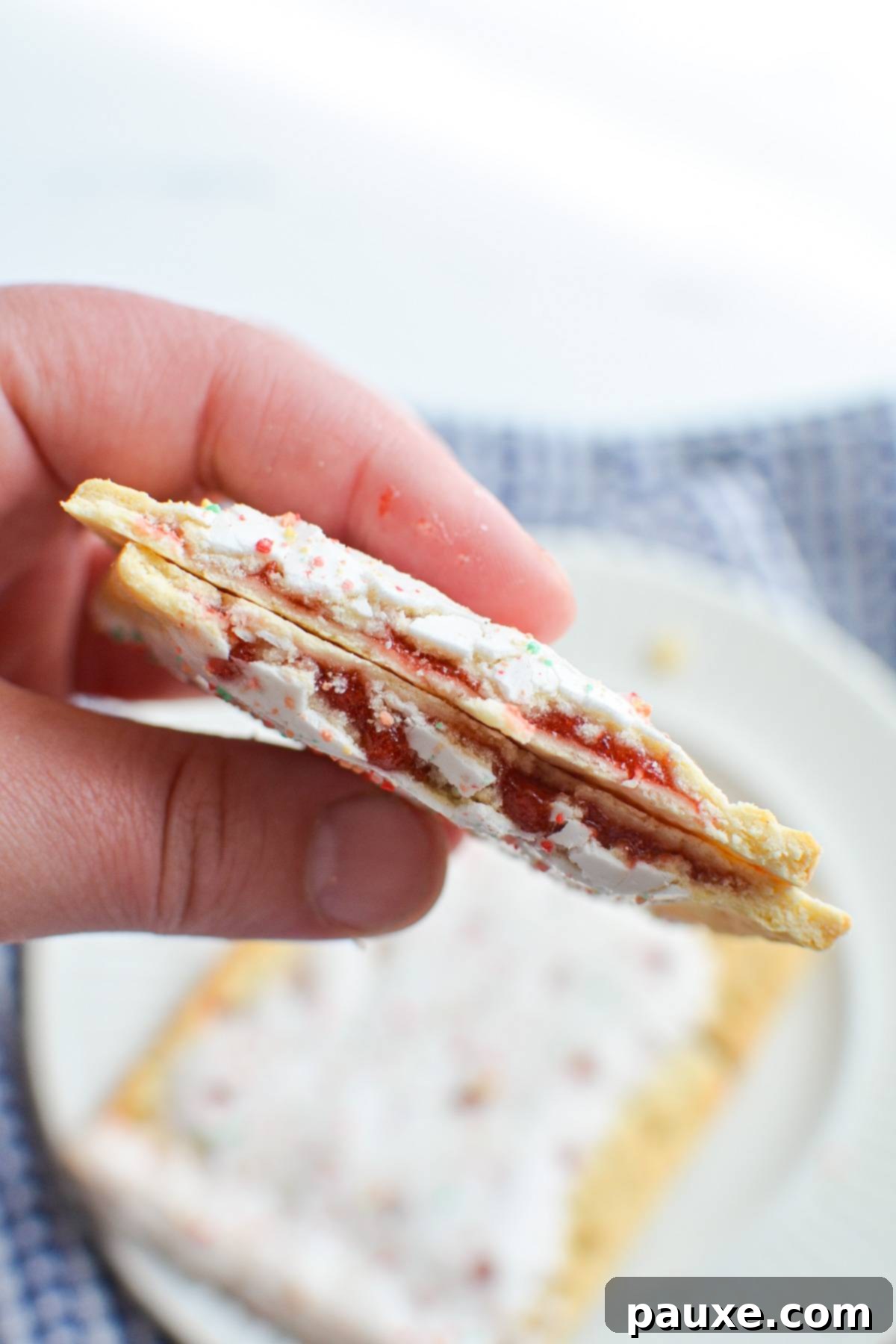 Air Fryer Toaster Pastries 6 A hand holding pop tarts with a strawberry filling.