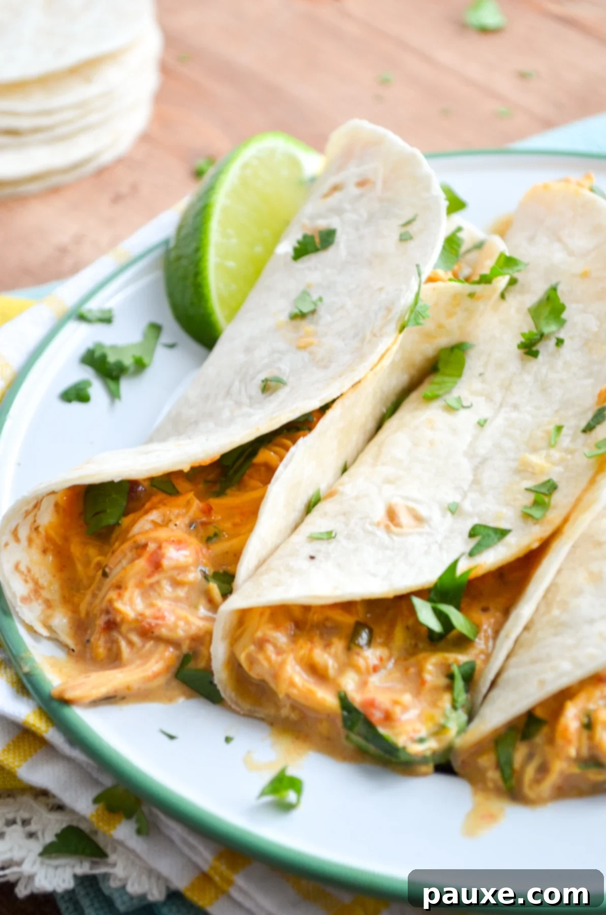 Creamy Slow Cooker Queso Chicken Tacos 3 Close-up of Slow Cooker Queso Chicken Tacos, garnished with fresh lime and cilantro, showing the rich, creamy texture.