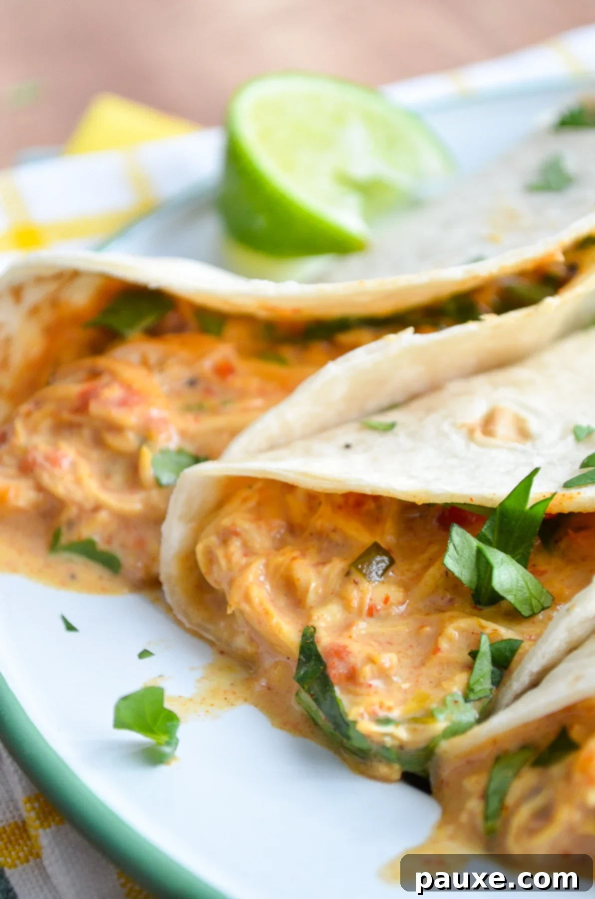Creamy Slow Cooker Queso Chicken Tacos 8 A beautifully arranged plate of Slow Cooker Queso Chicken Tacos, garnished with fresh lime and cilantro, showcasing the rich filling.