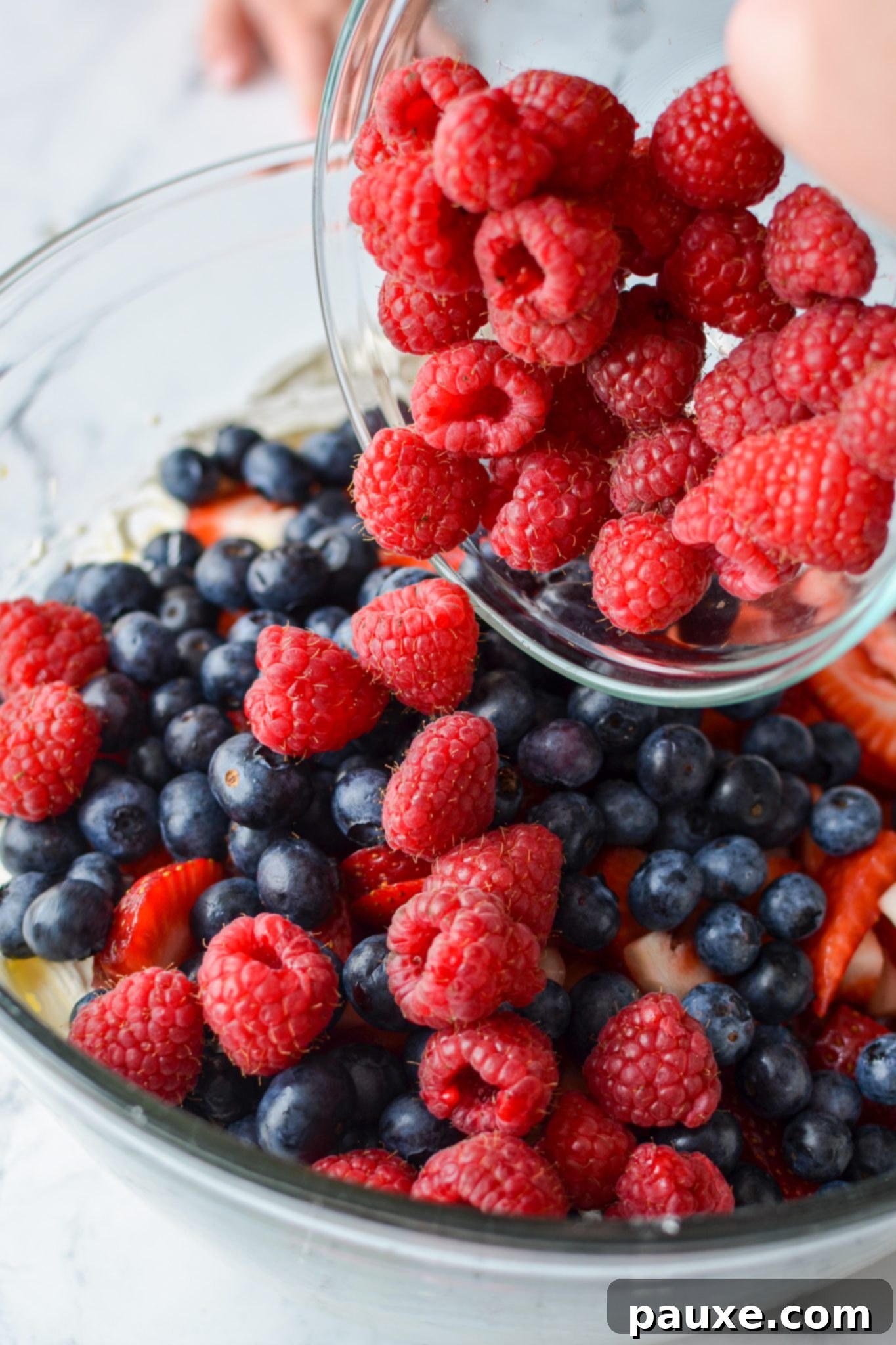 Red, White, and Blue Cheesecake Berry Bliss 8 Adding fresh berries to a bowl.