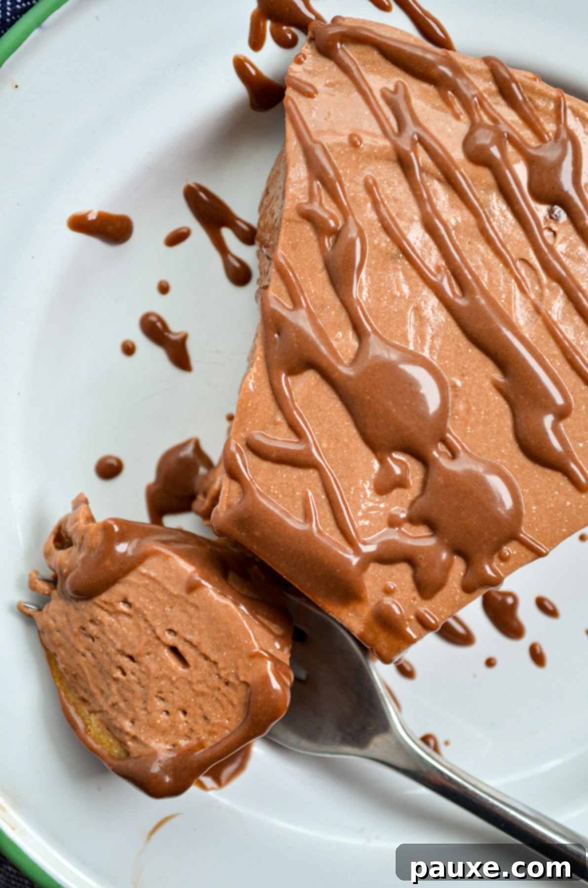 A beautifully presented slice of Nutella pie, with a generous drizzle of ganache, on a white plate.