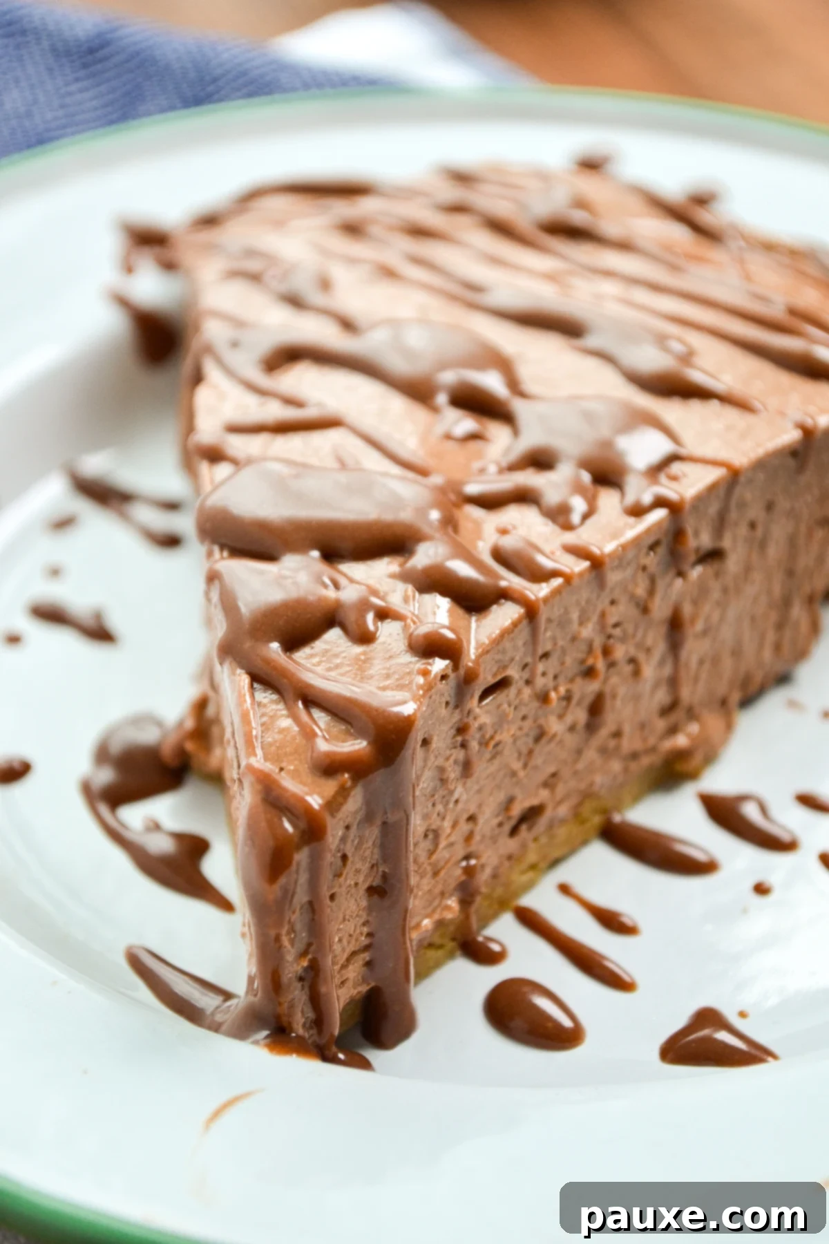 A slice of nutella pie topped with a shiny nutella ganache, ready to be enjoyed.